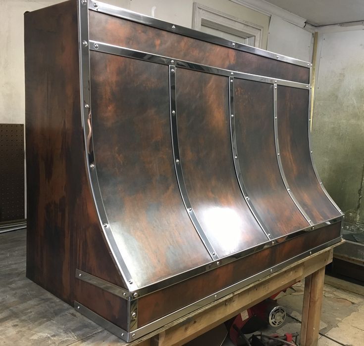 A copper hood is sitting on top of a wooden table.