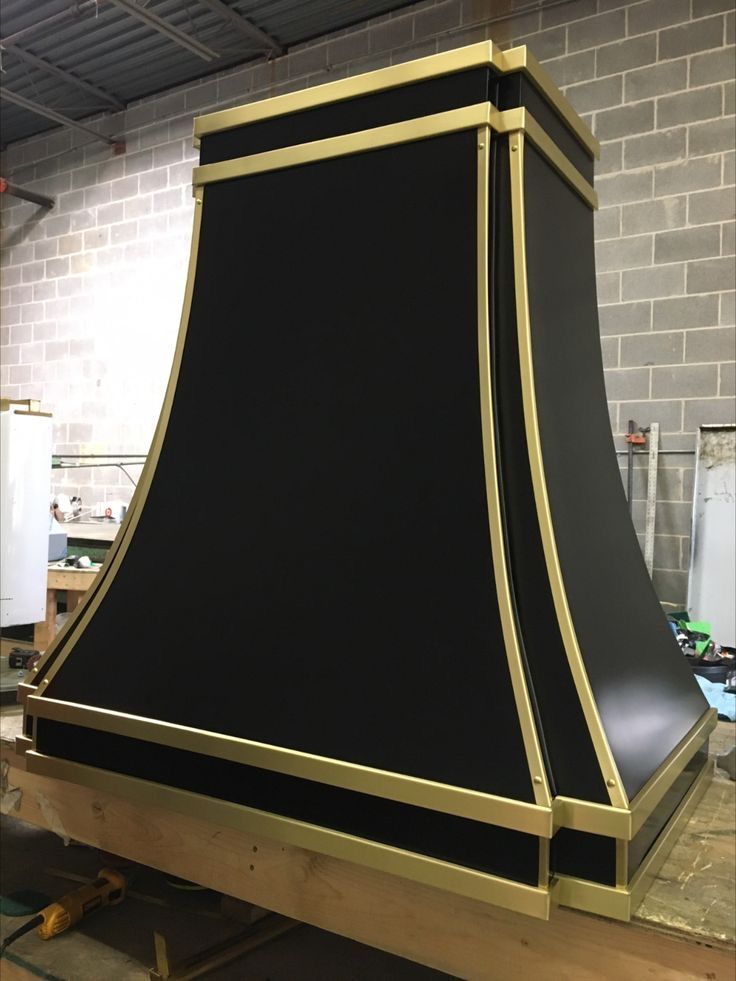 A black and gold hood is sitting on a wooden table.