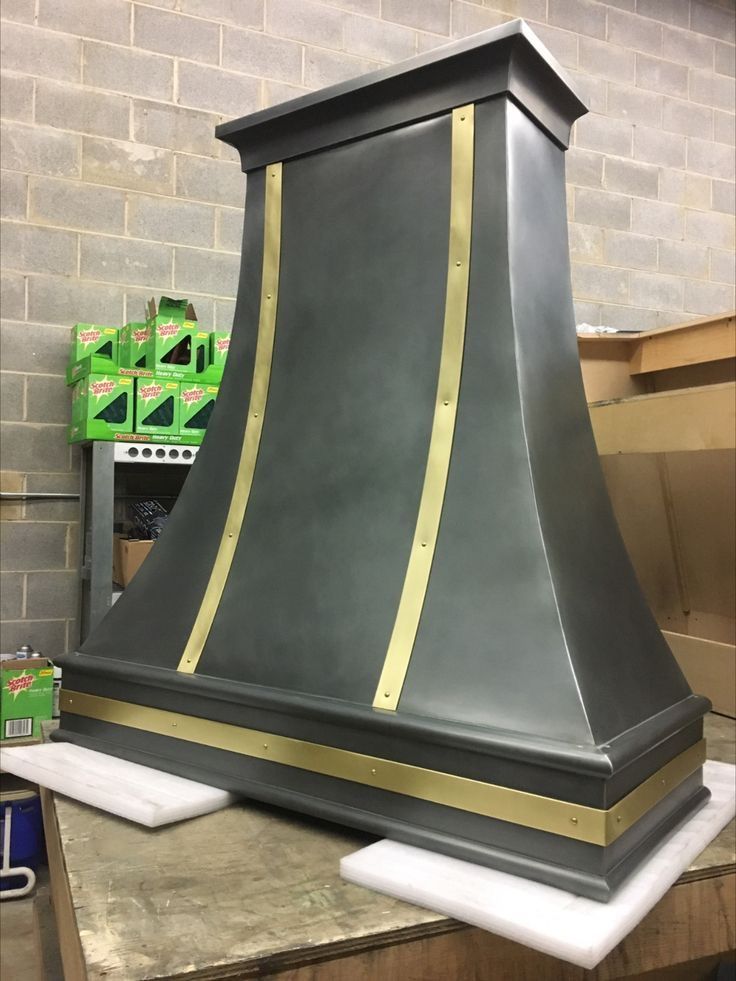 A gray and gold hood is sitting on top of a wooden table.