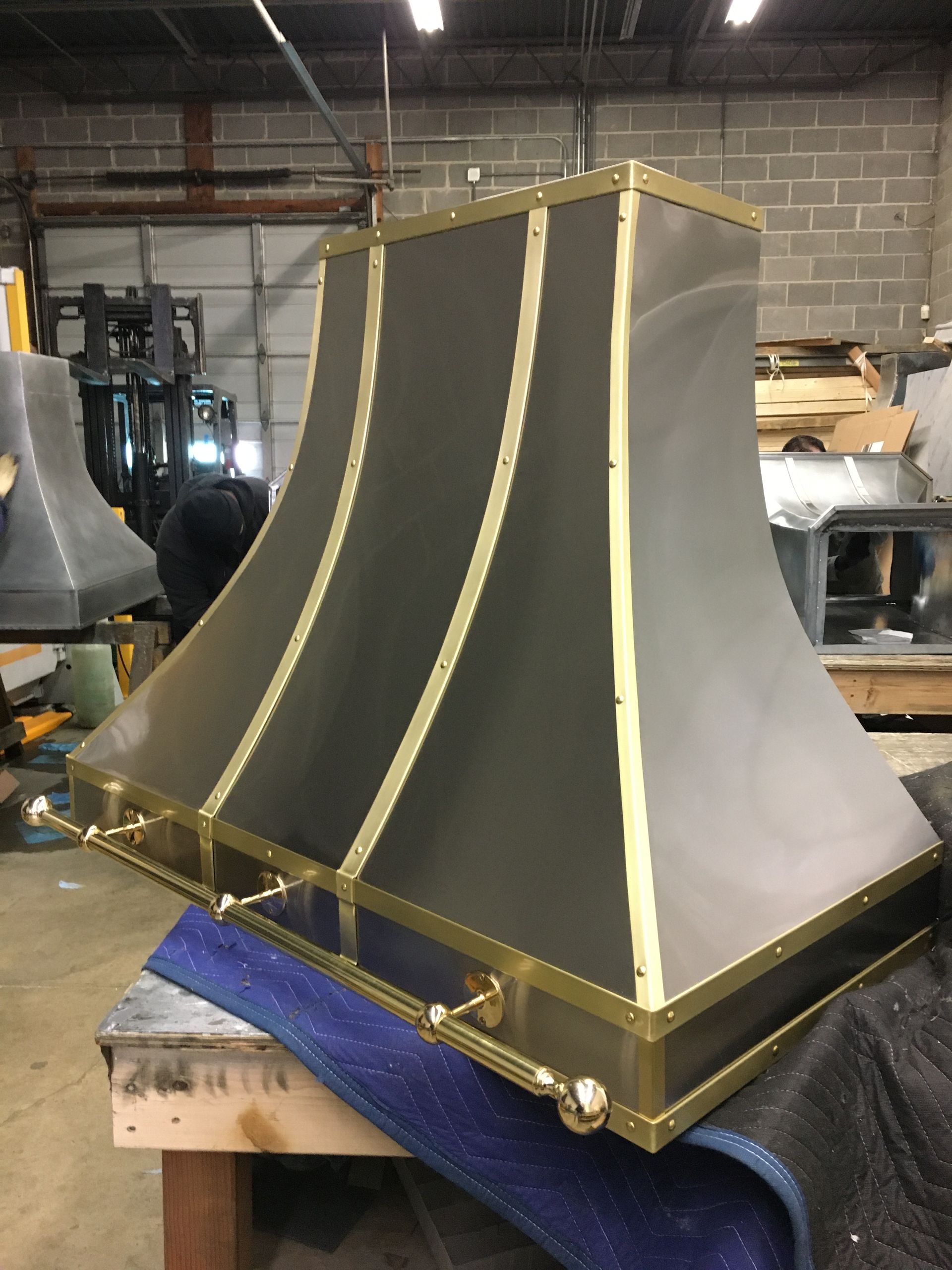 A stainless steel hood with brass trim sits on a table