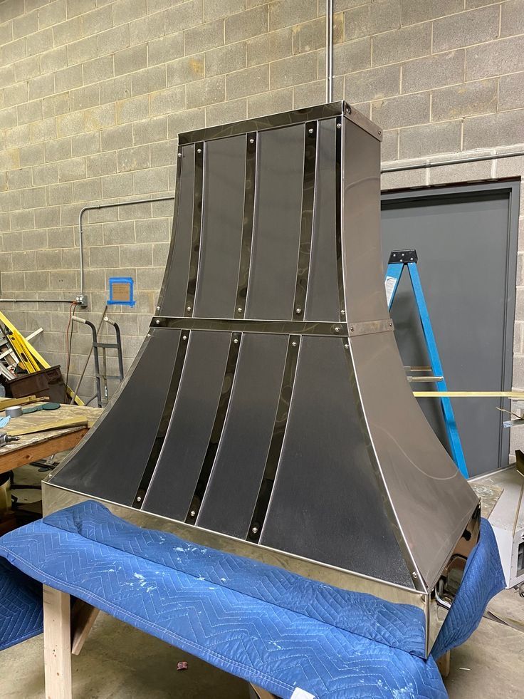 A stainless steel hood is sitting on top of a blue table.