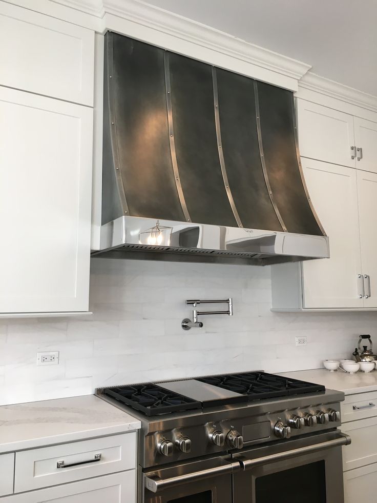 A kitchen with a stove top oven and a stainless steel hood.