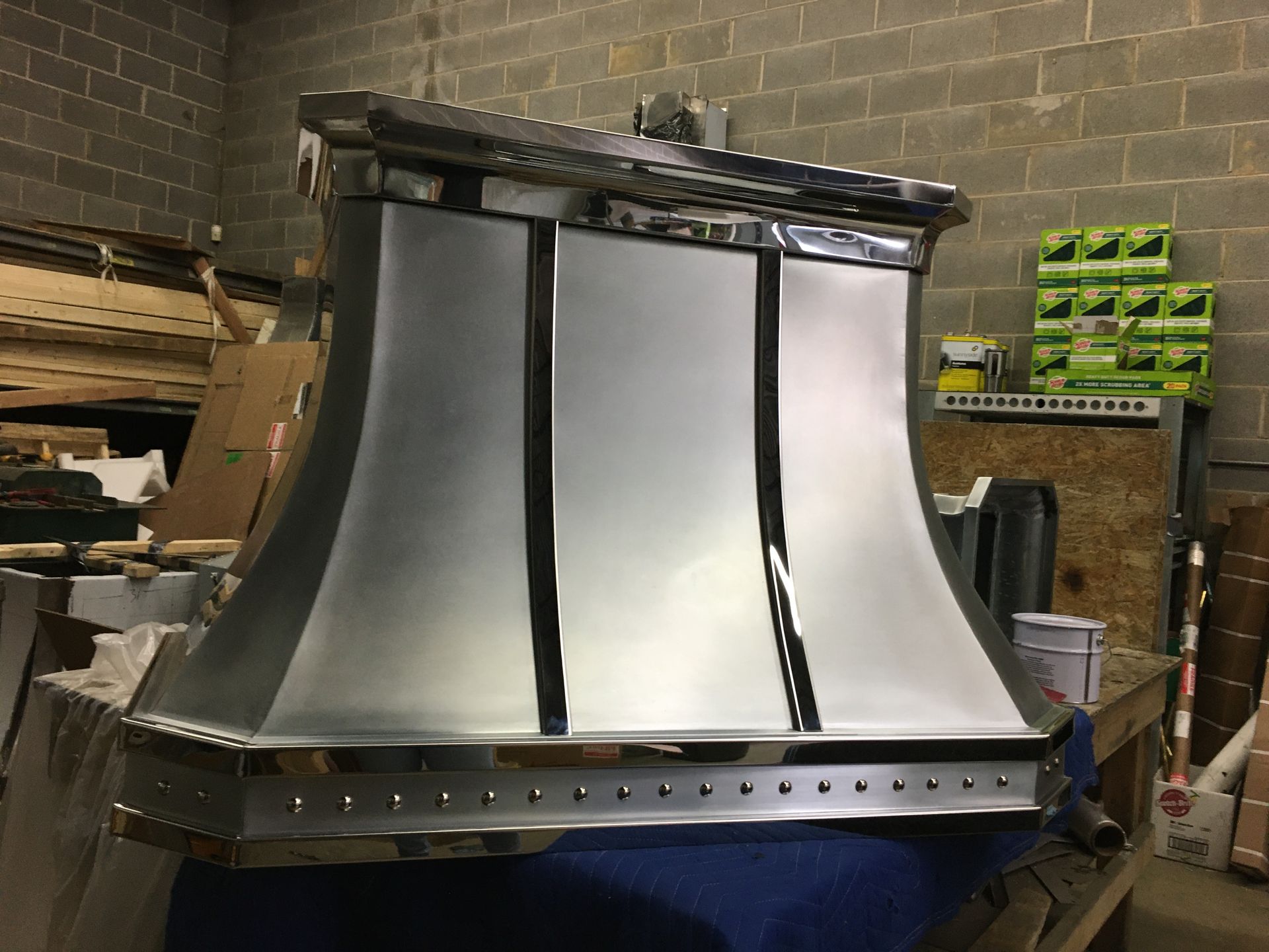 A stainless steel hood is sitting on a table in a warehouse.