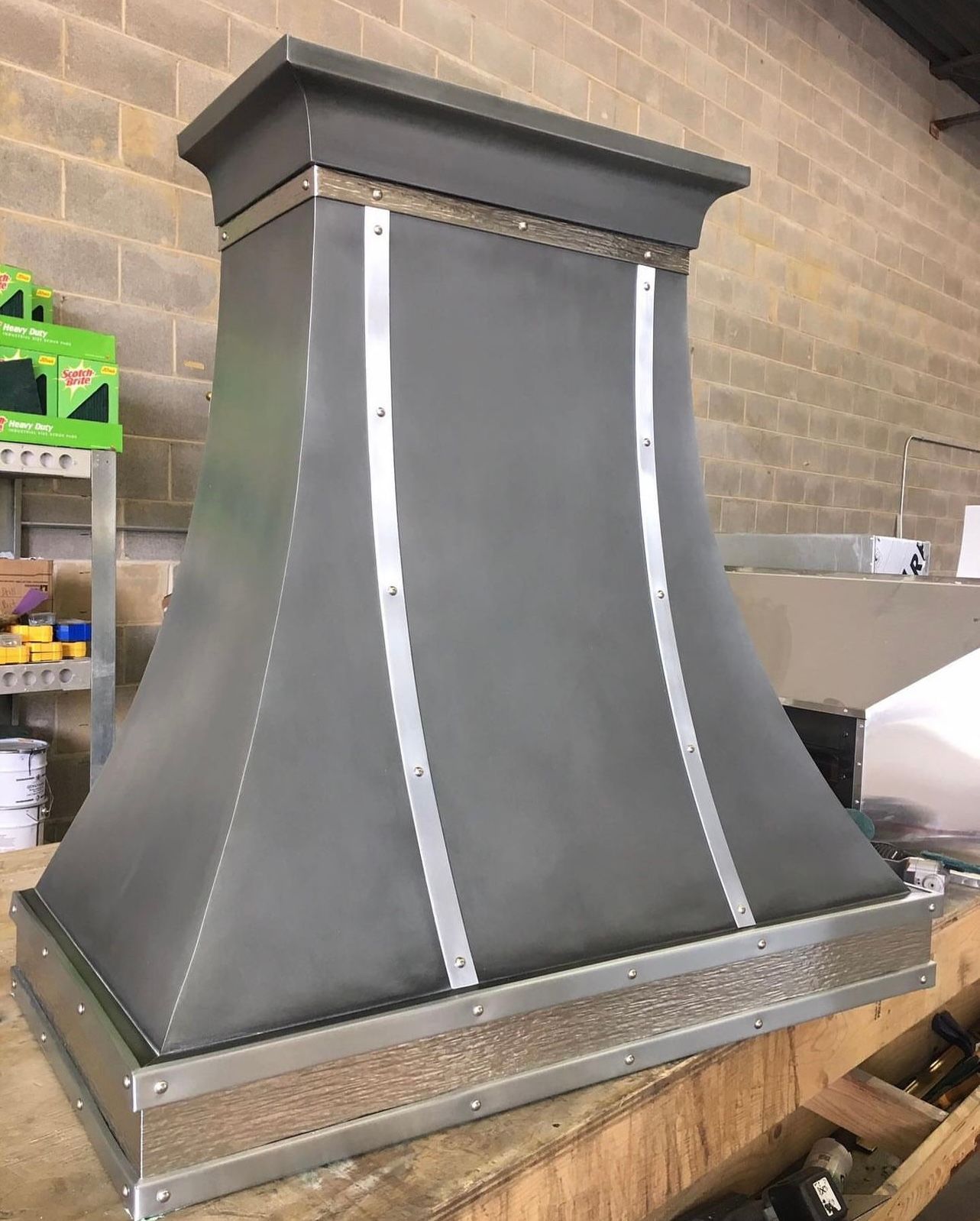 A metal hood is sitting on top of a wooden table.
