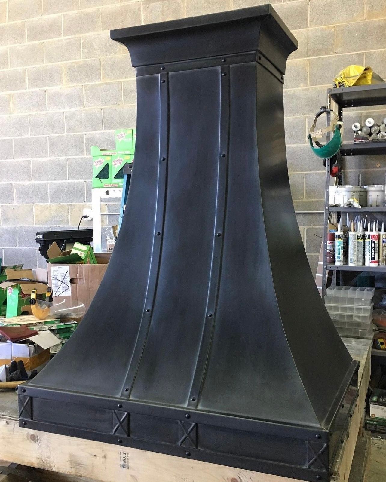 A large black chimney is sitting on top of a wooden table in front of a brick wall.