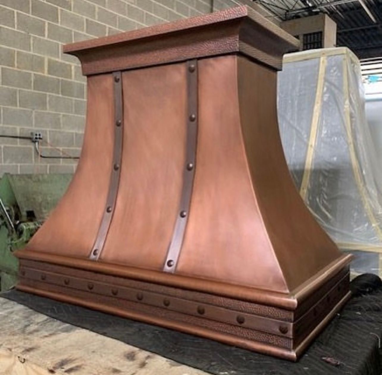 A copper hood is sitting on top of a wooden table