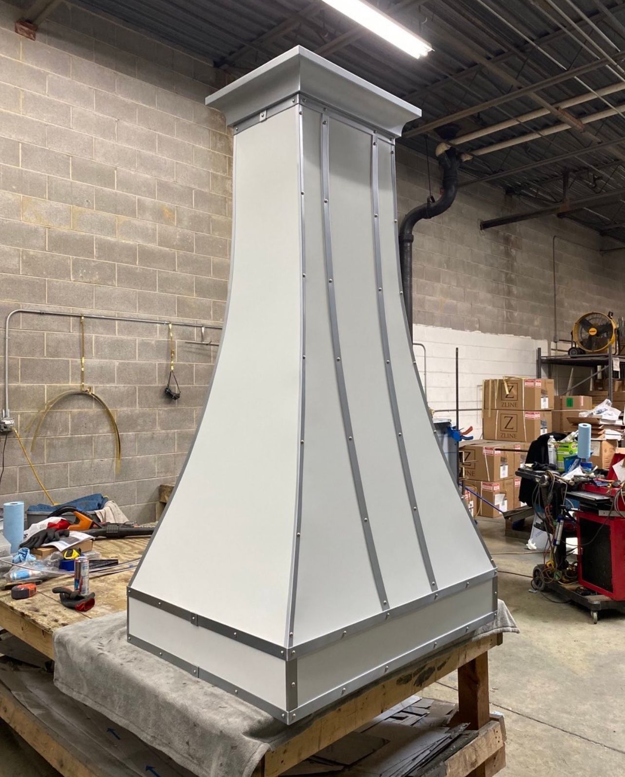 A white hood is sitting on top of a wooden table in a warehouse.