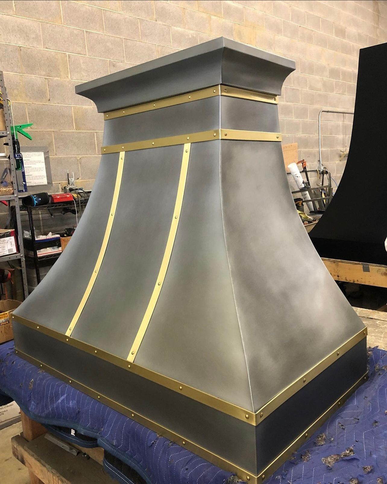 A stainless steel hood is sitting on top of a blue tarp on a table.