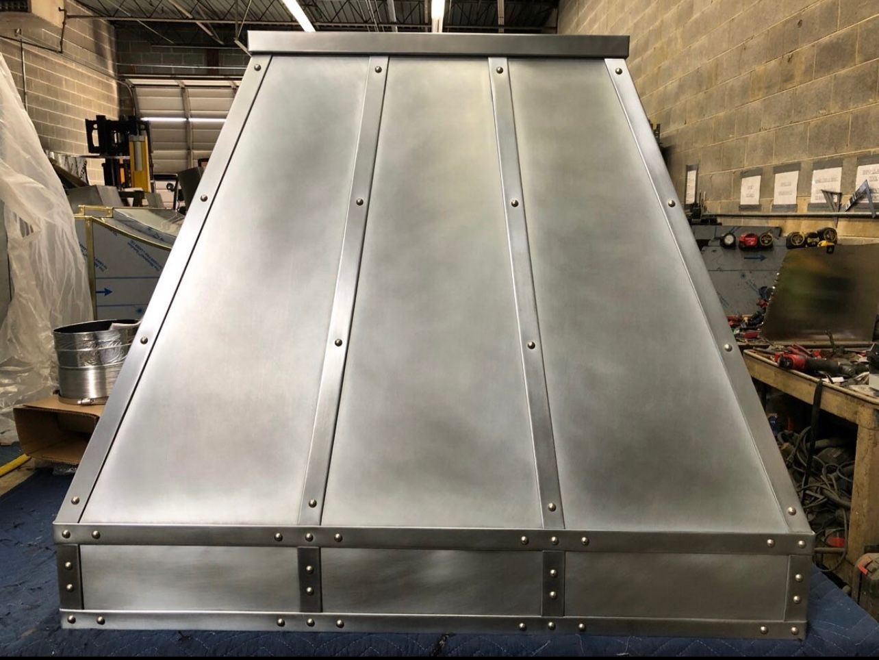 A metal hood is sitting on a blue table in a room.