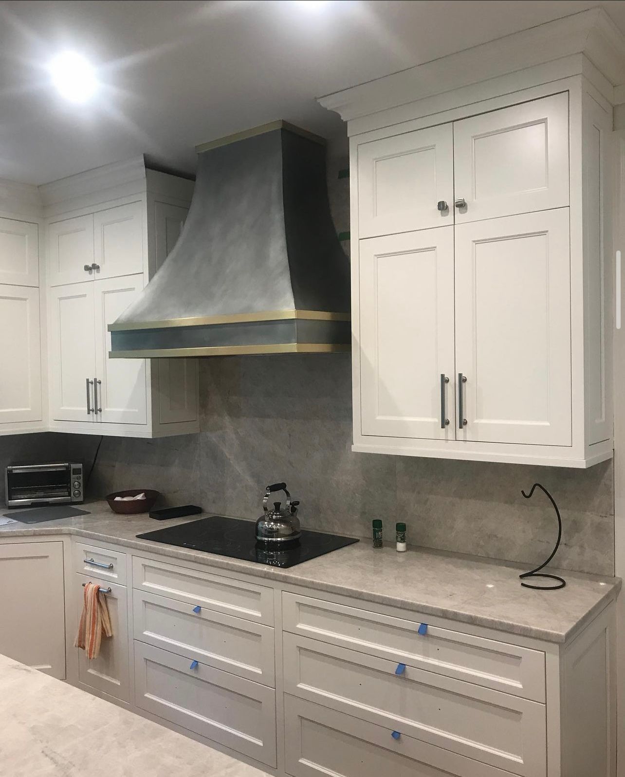 A kitchen with white cabinets and a stove top oven.