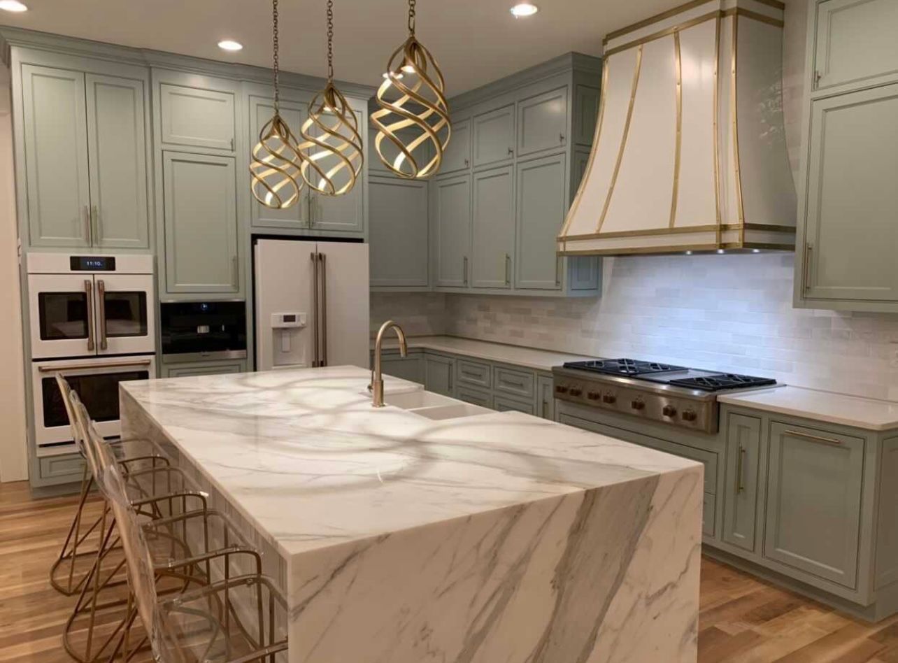 A kitchen with a large island and marble counter tops.