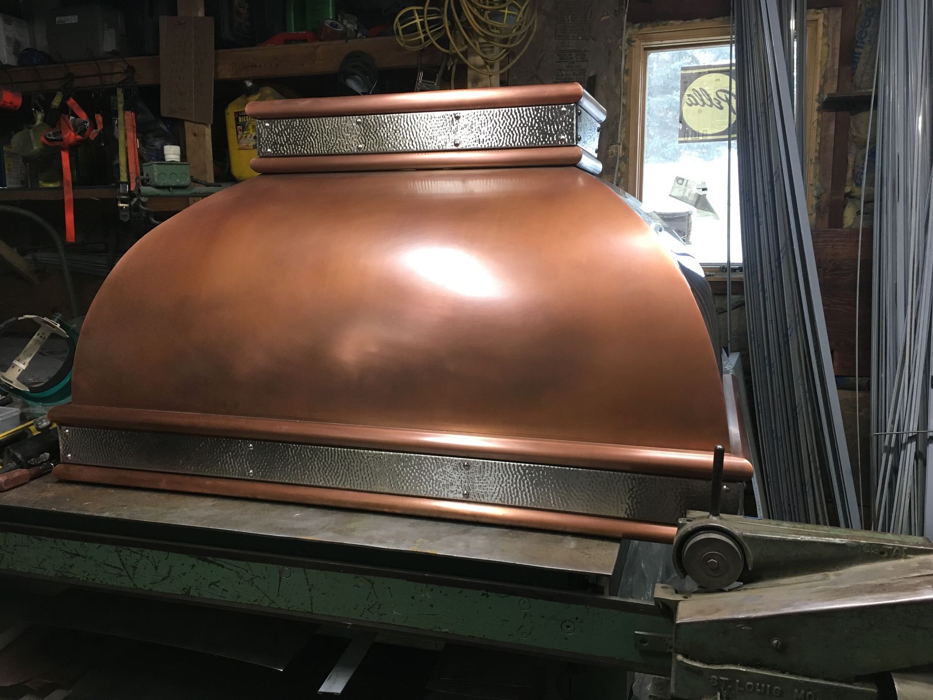 A copper hood is sitting on top of a machine in a garage.