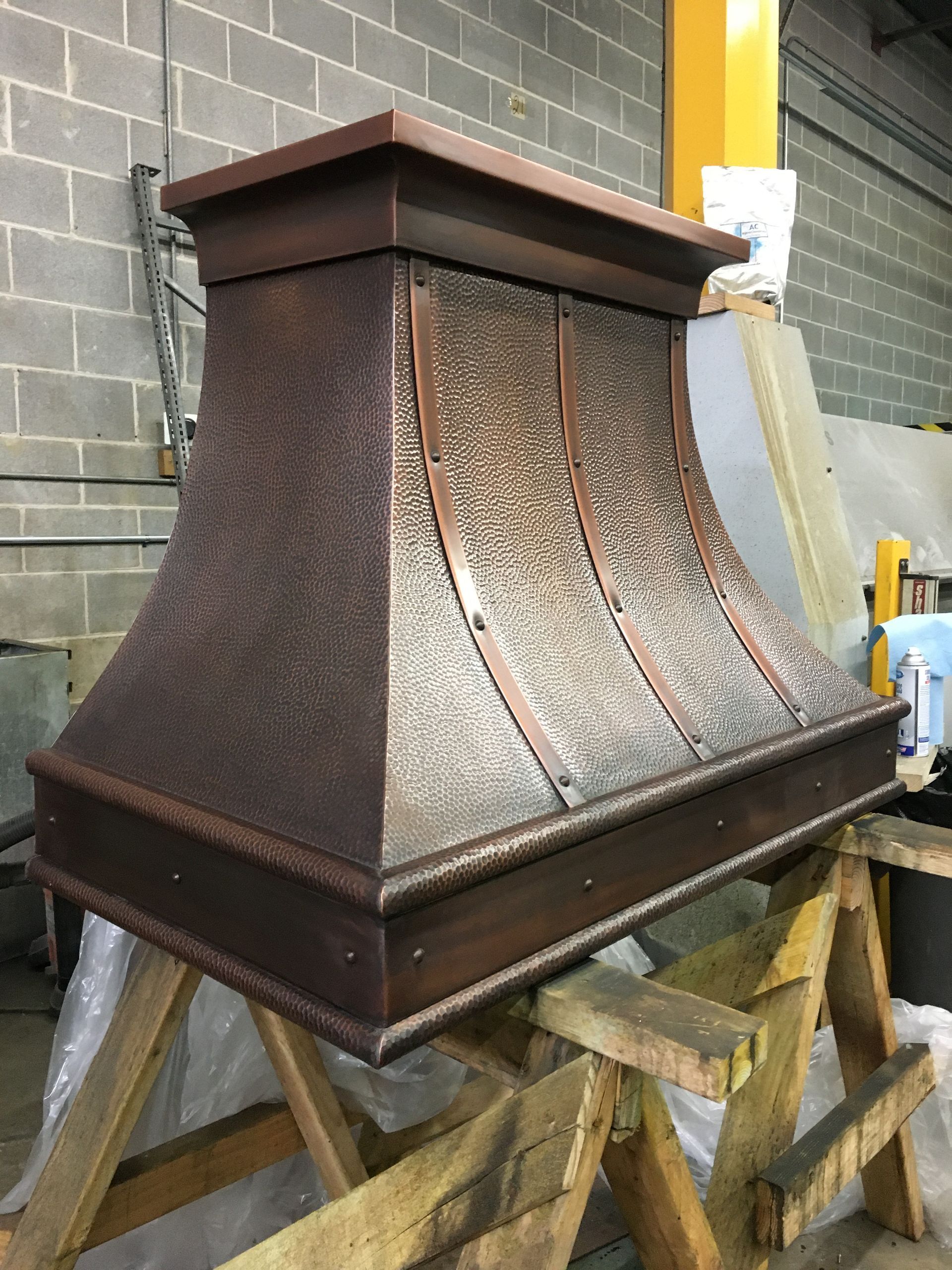 A copper hood is sitting on top of a wooden table.