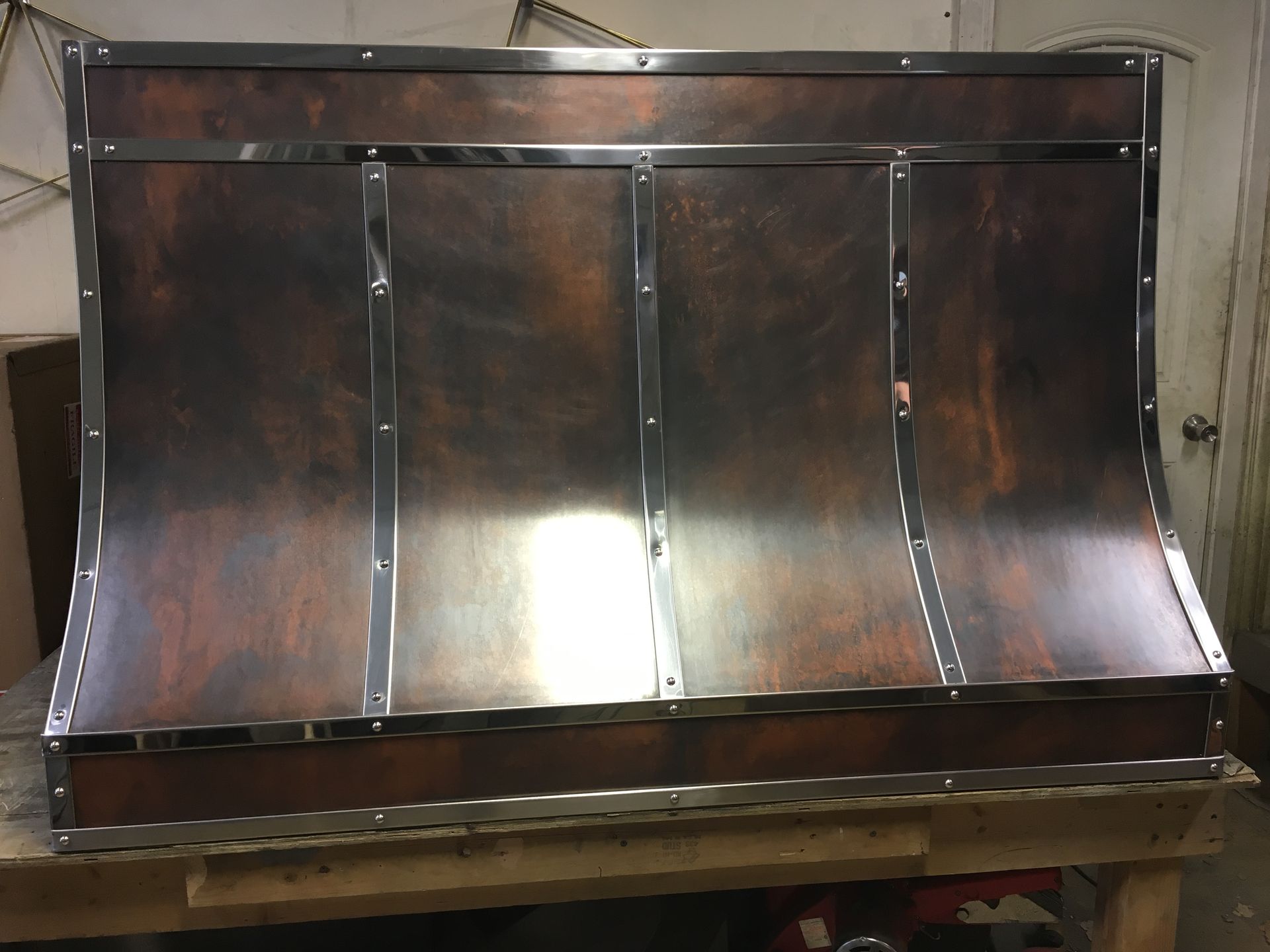 A copper hood is sitting on top of a wooden table.