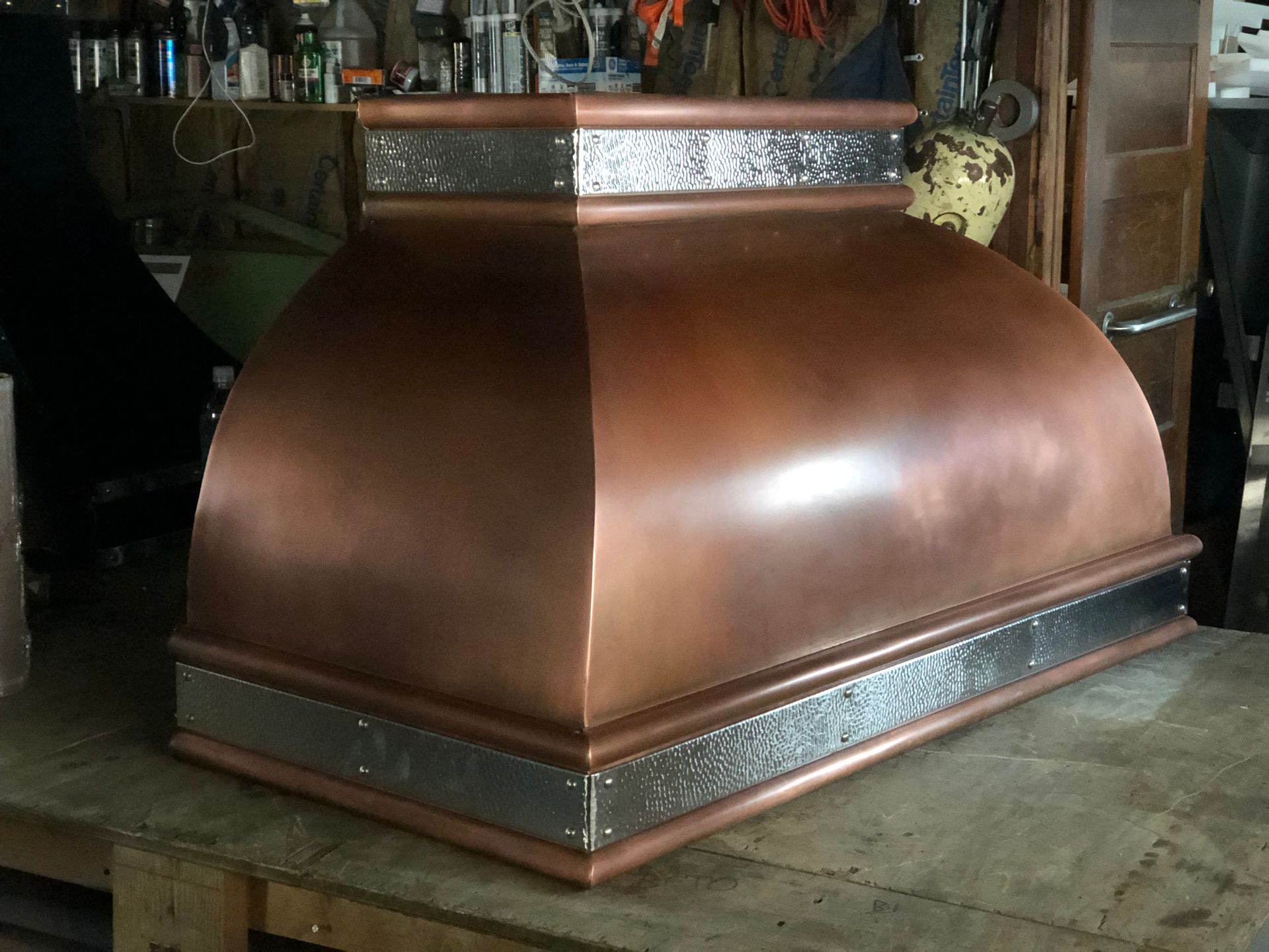 A copper hood is sitting on top of a wooden table.
