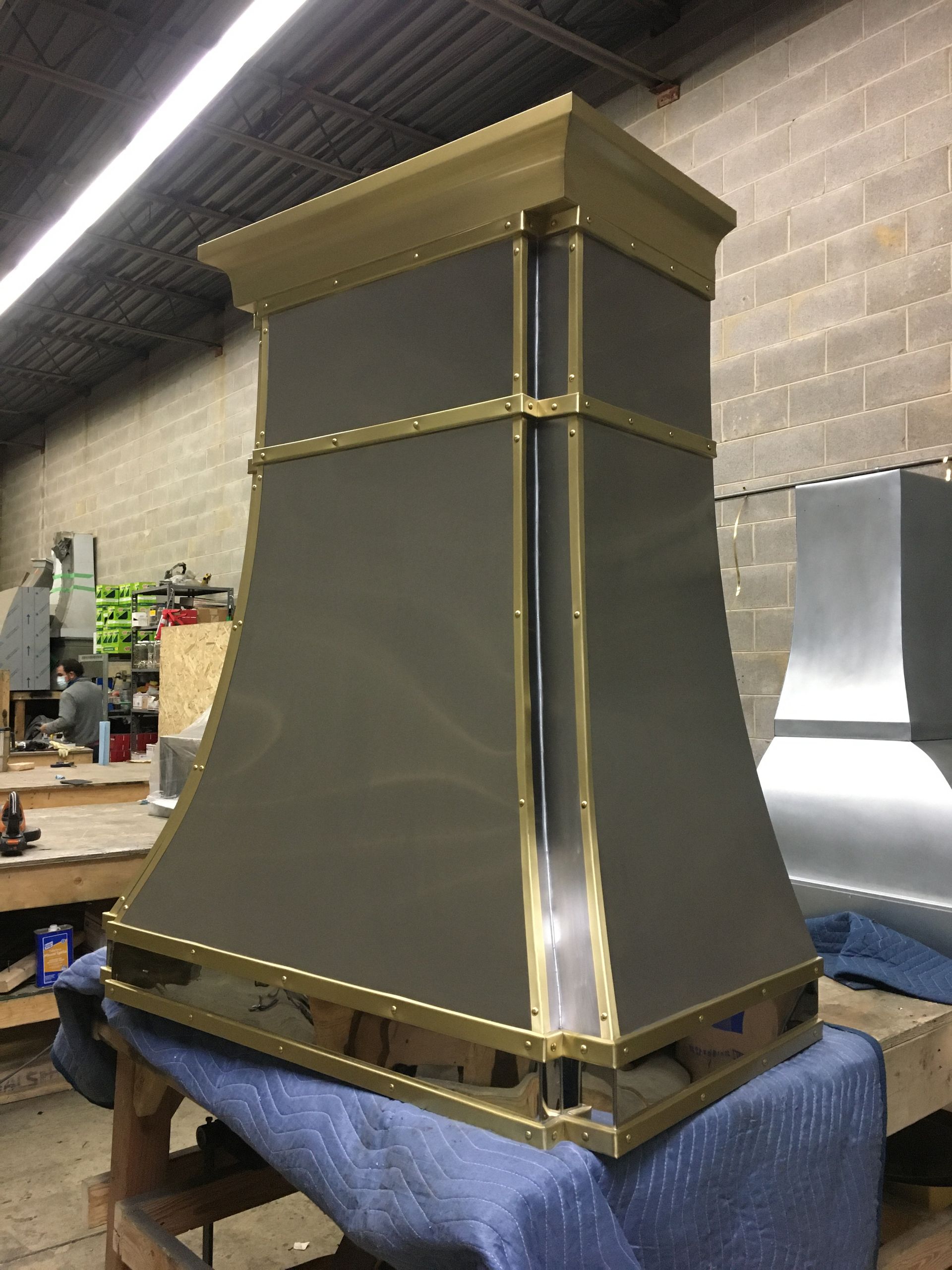 A brass and stainless steel hood is sitting on a table.