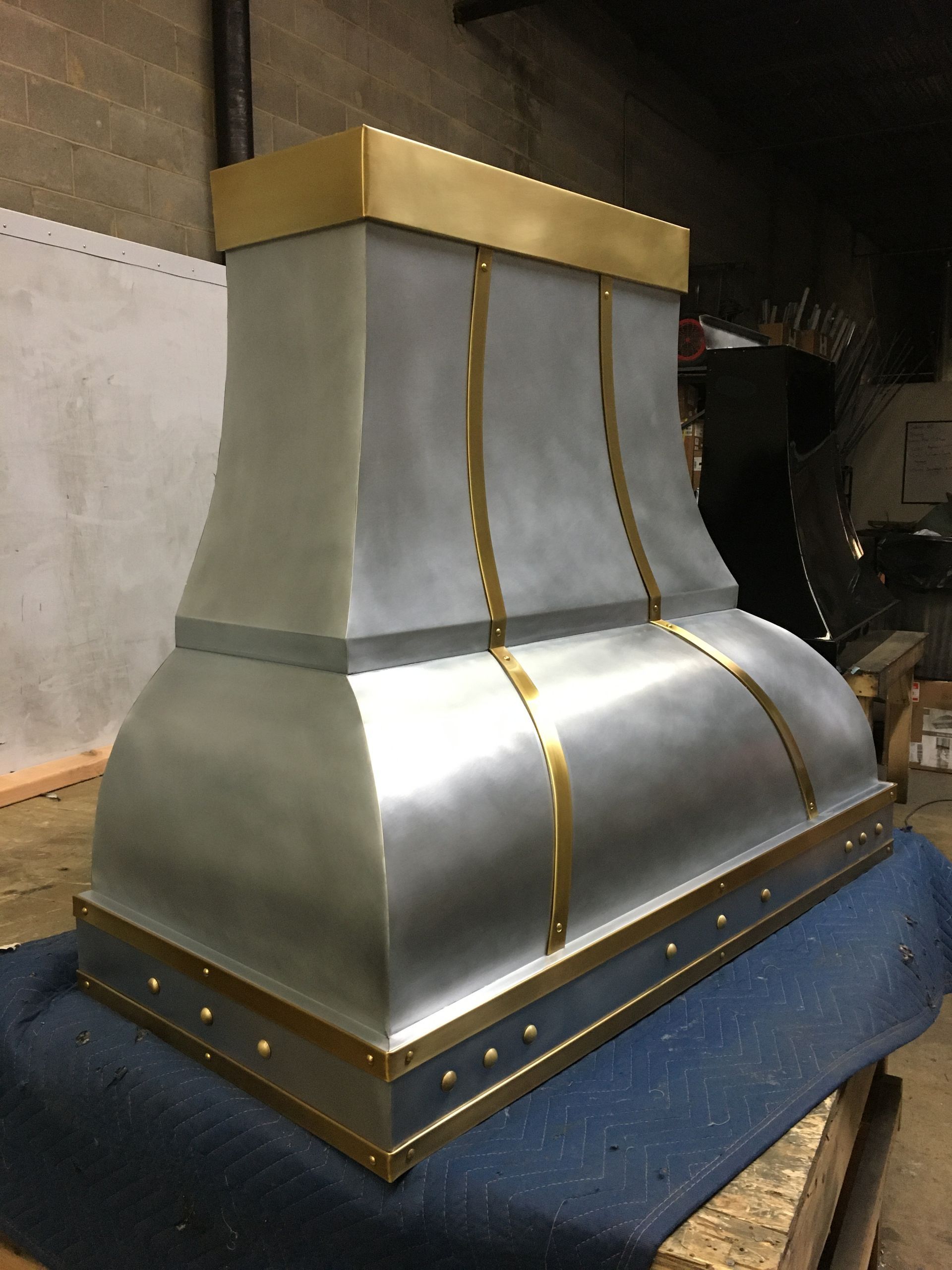 A stainless steel hood with brass trim is sitting on a table.