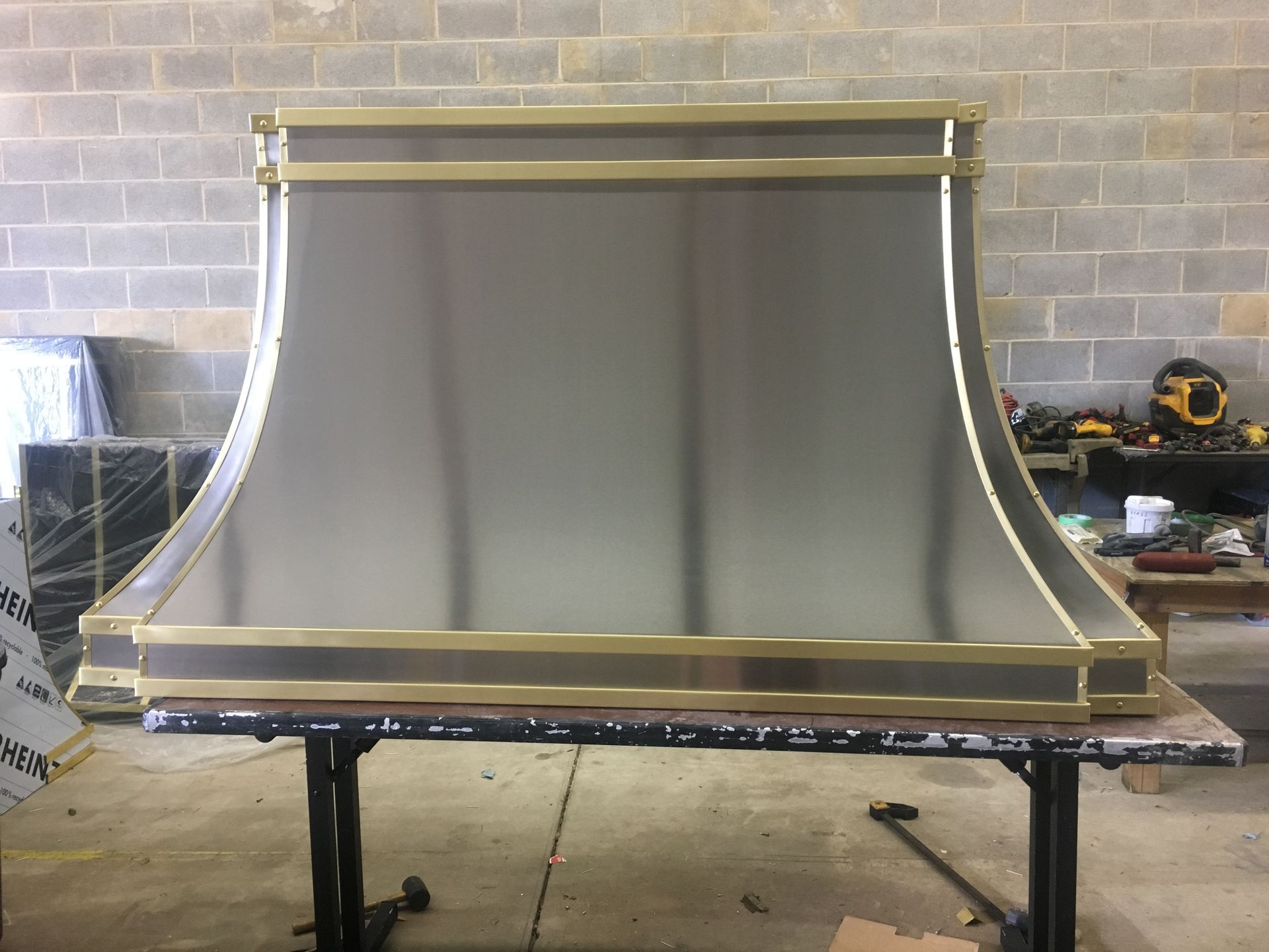 A stainless steel hood with brass trim is sitting on a table.
