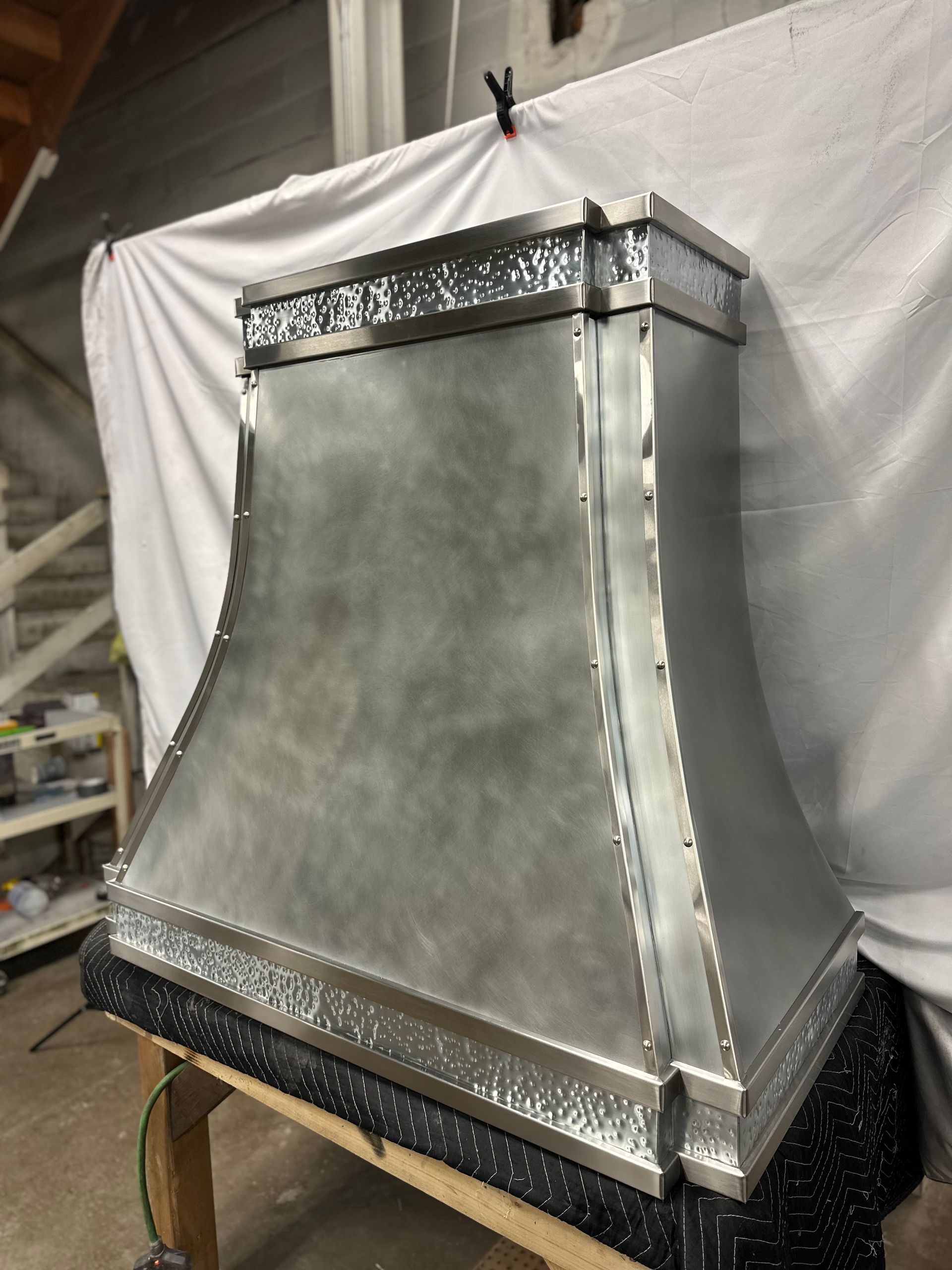 A metal hood is sitting on top of a wooden table.