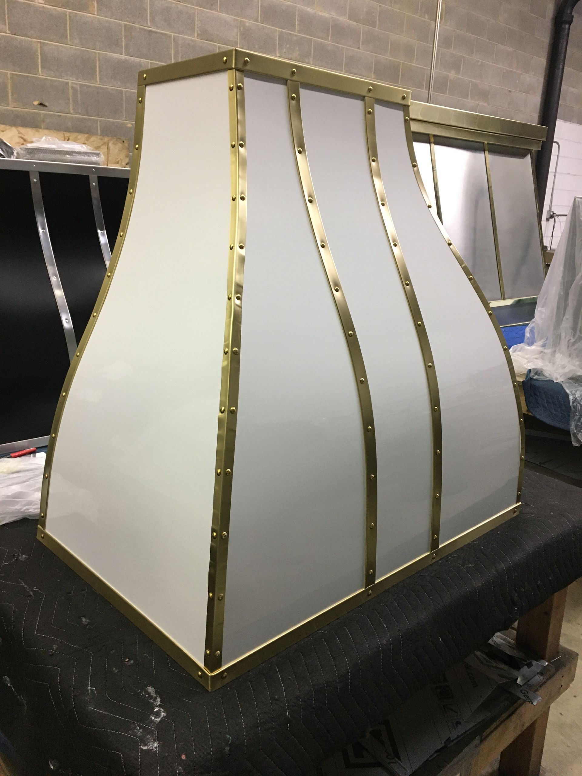 A white hood with brass trim is sitting on a table.
