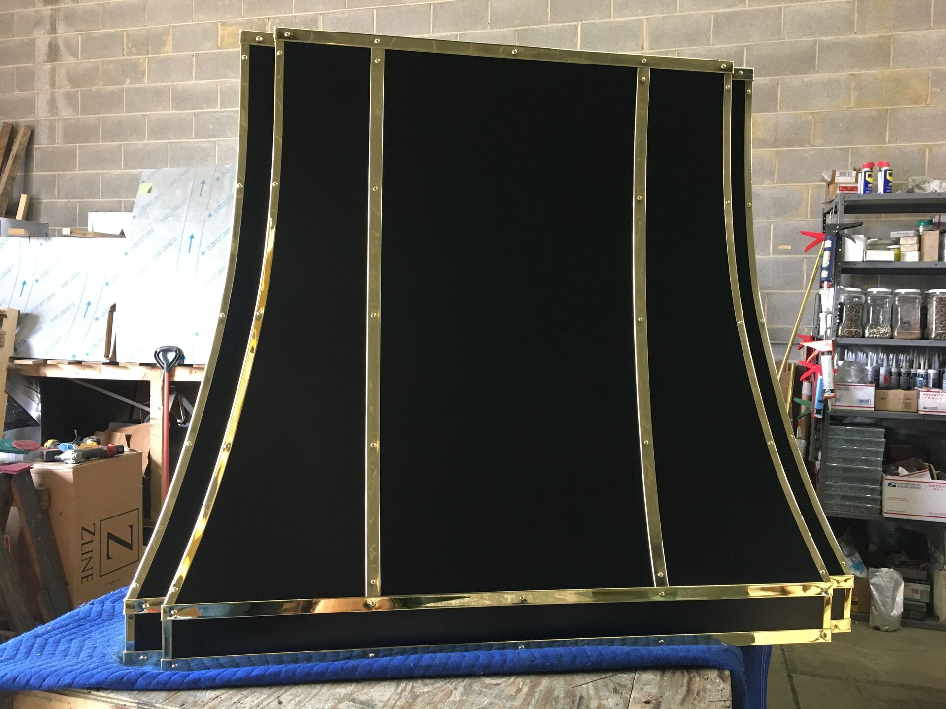 A black lampshade with gold trim is sitting on a blue table.