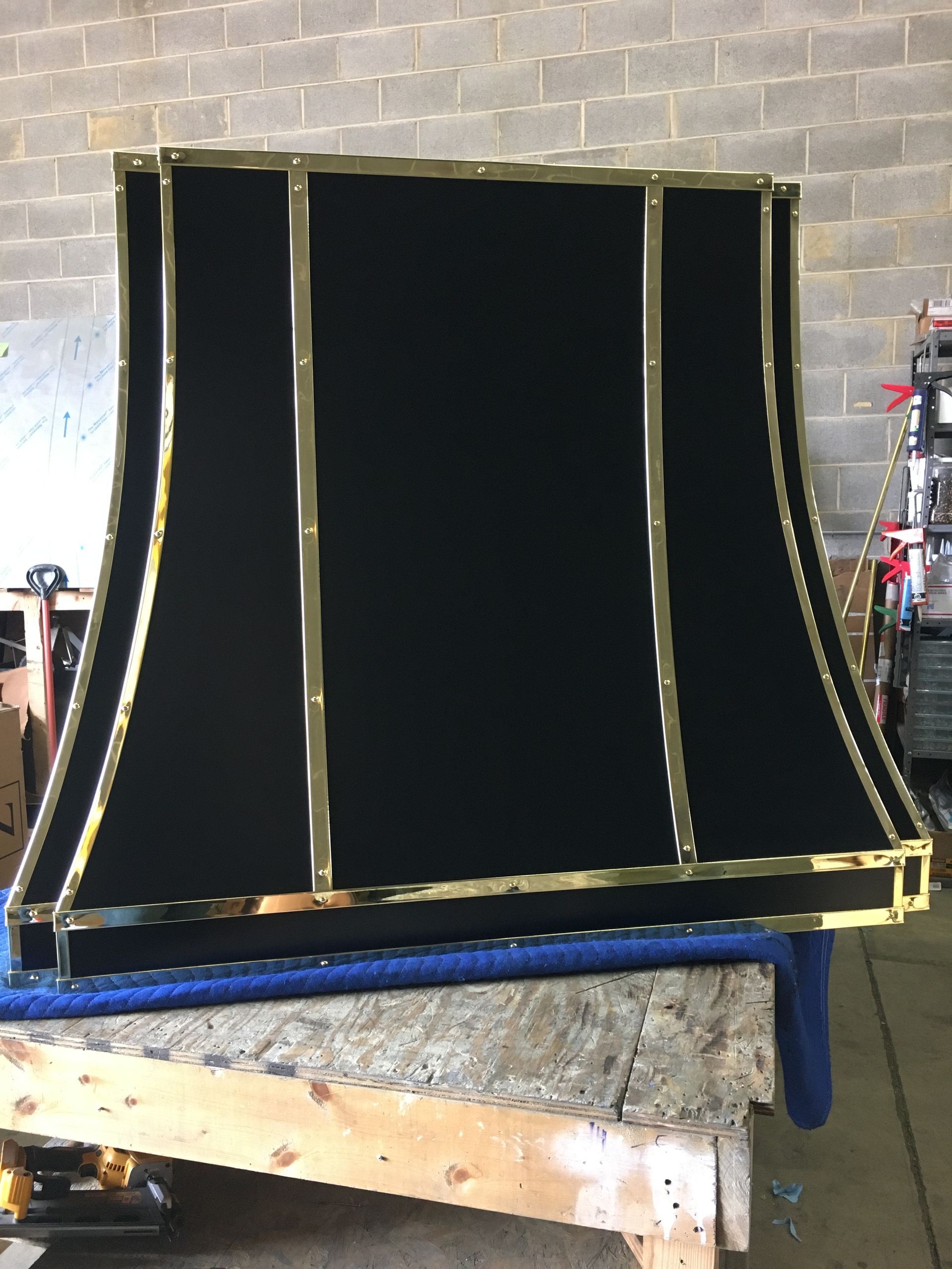 A black lampshade with gold trim is sitting on a wooden table.
