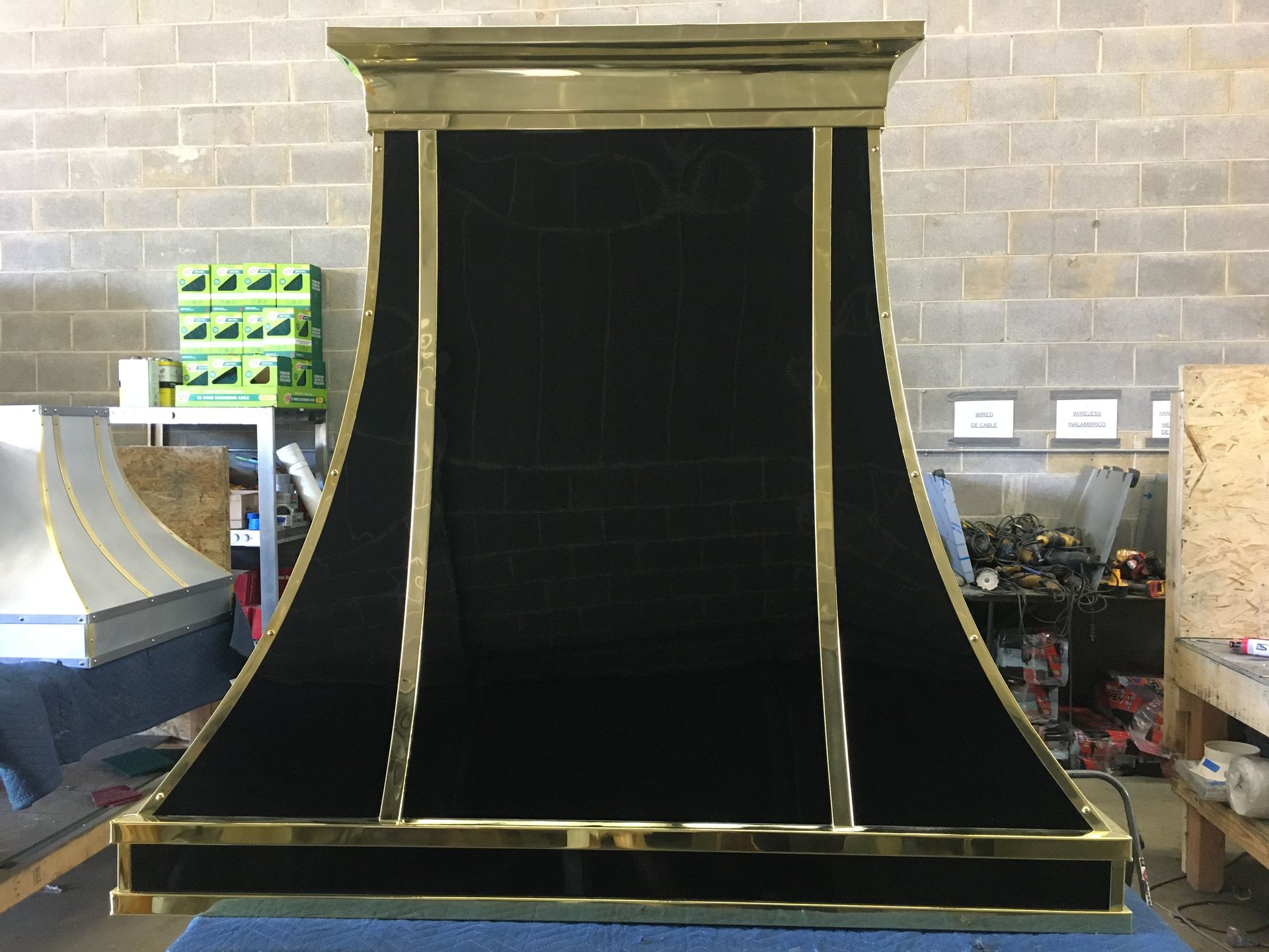 A black and gold hood is sitting on a table in front of a brick wall.