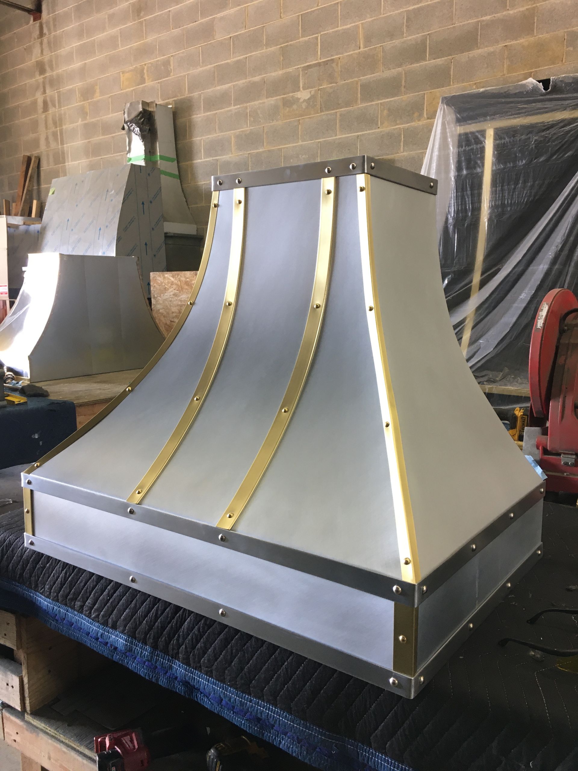 A stainless steel hood with gold trim is sitting on a table.