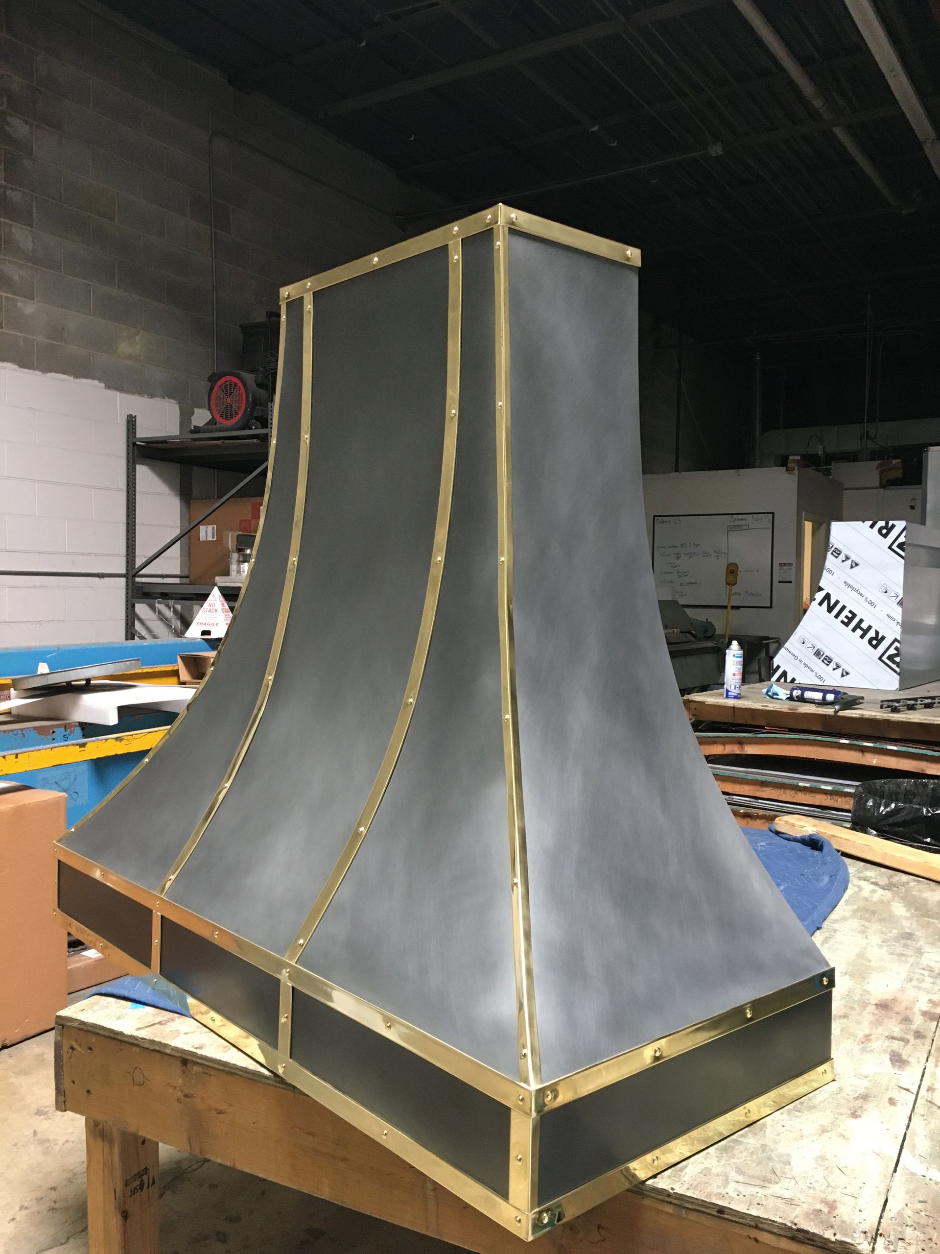 A gray and gold hood is sitting on a wooden table in a warehouse.