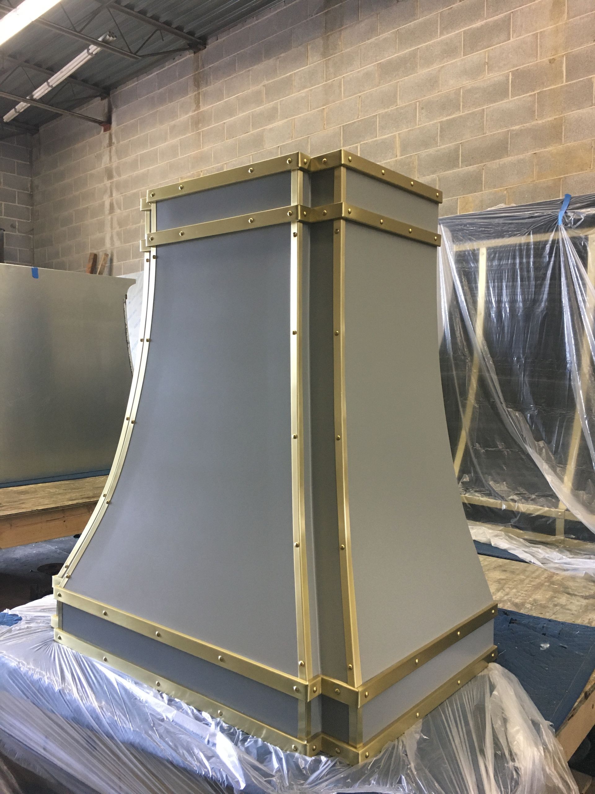 A gray and gold hood is sitting on a table in front of a brick wall.