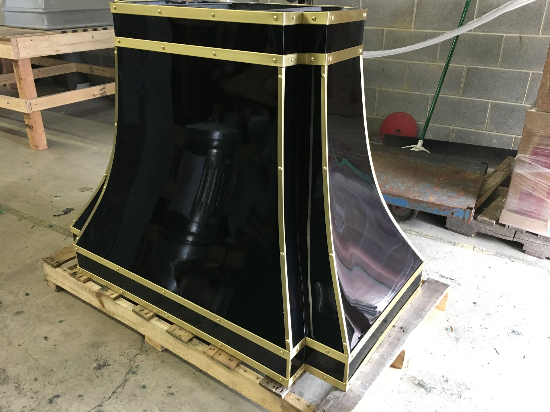 A black and gold hood is sitting on a wooden pallet.