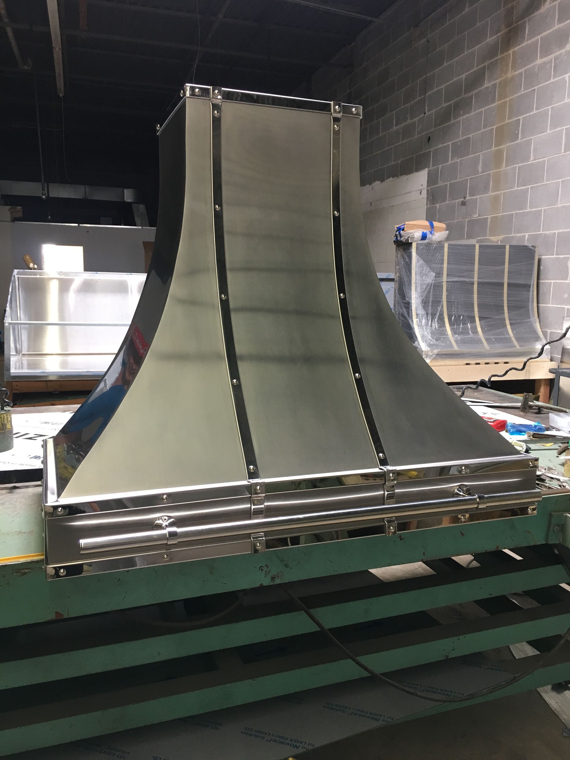 A stainless steel hood is sitting on top of a green table.