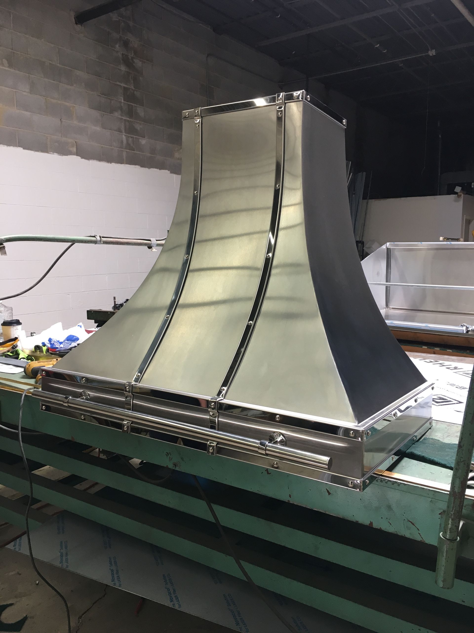 A stainless steel hood is sitting on top of a green table.