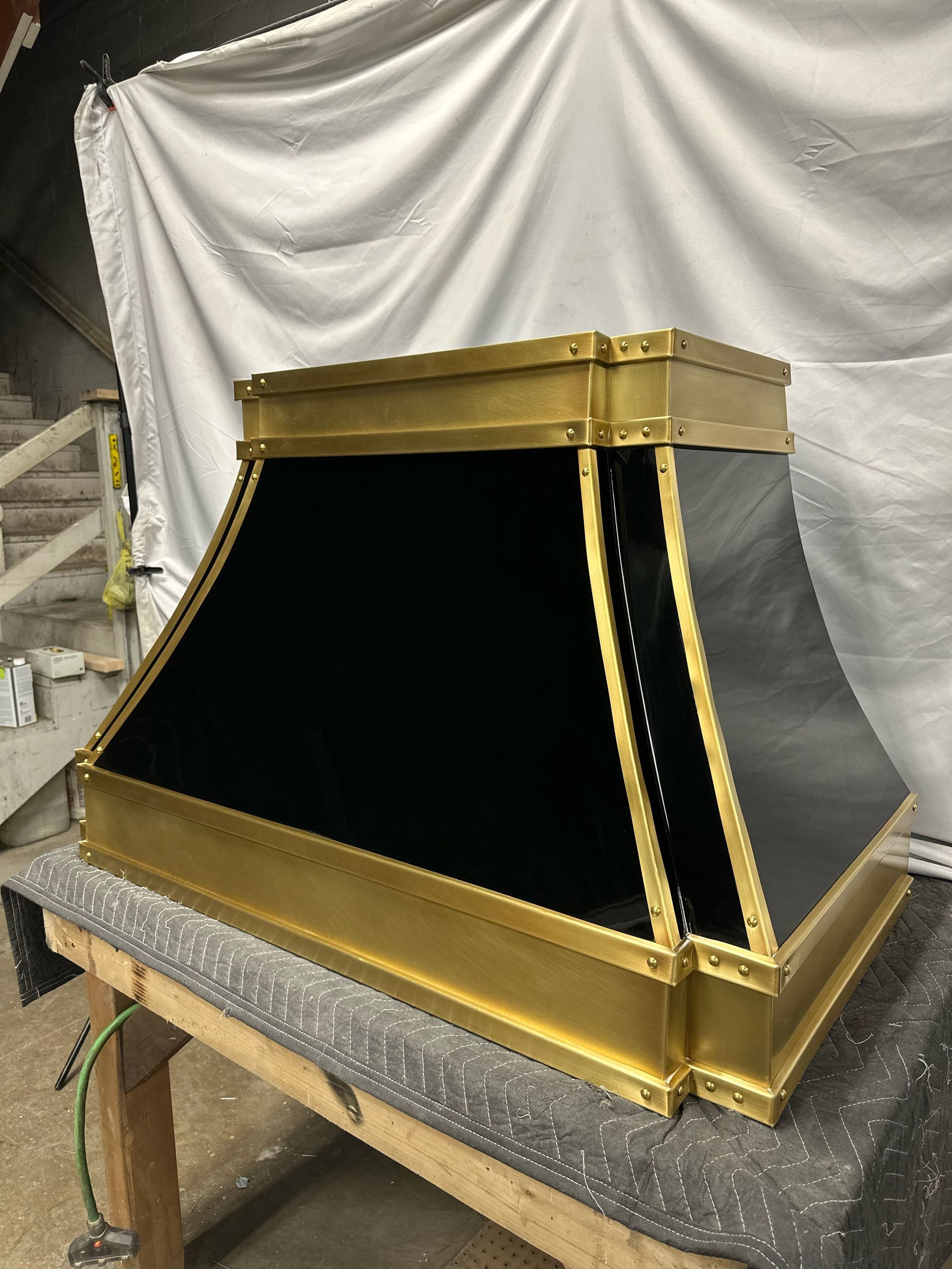 A black and gold hood is sitting on top of a wooden table.