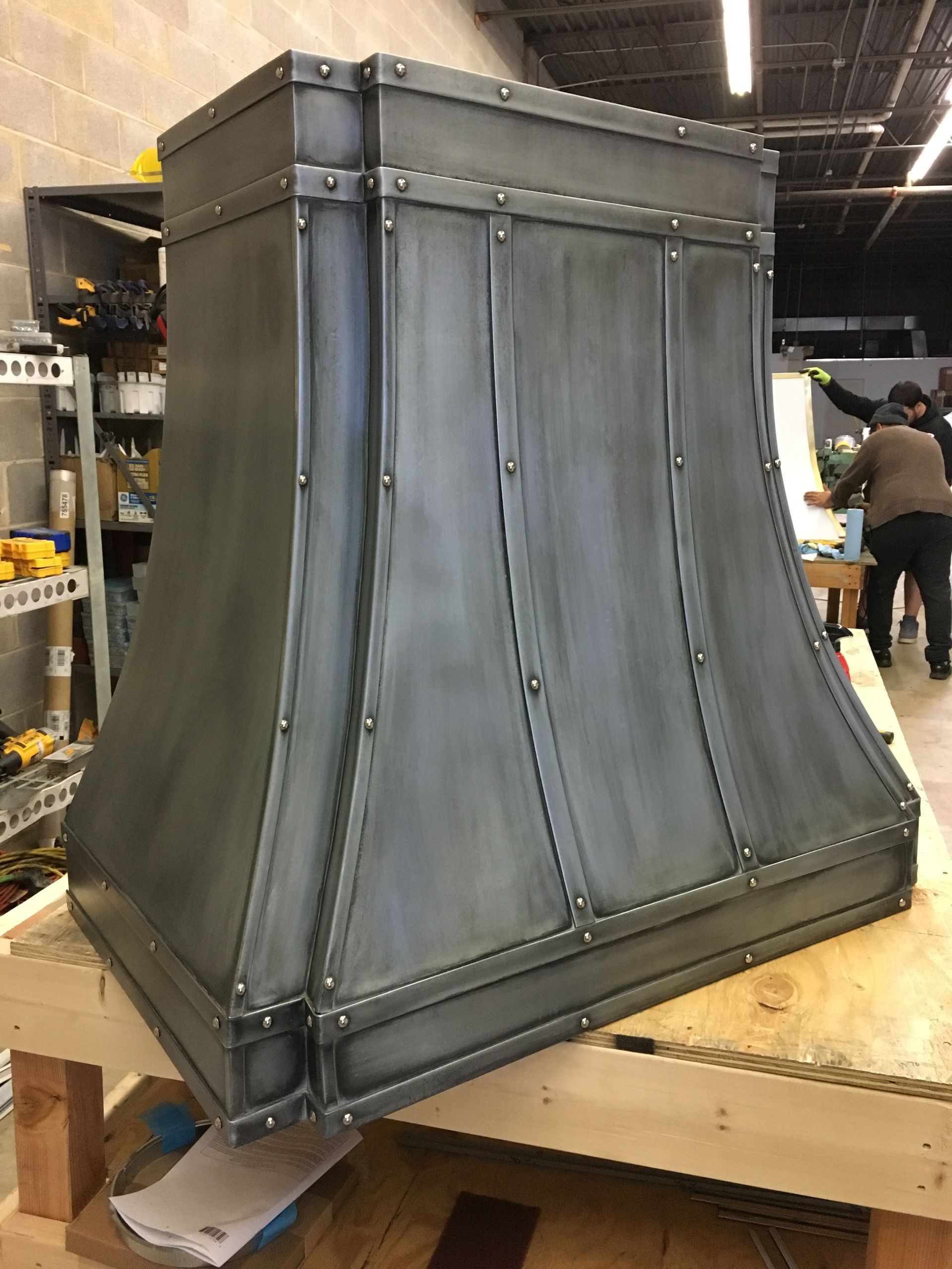 A metal hood is sitting on top of a wooden table.