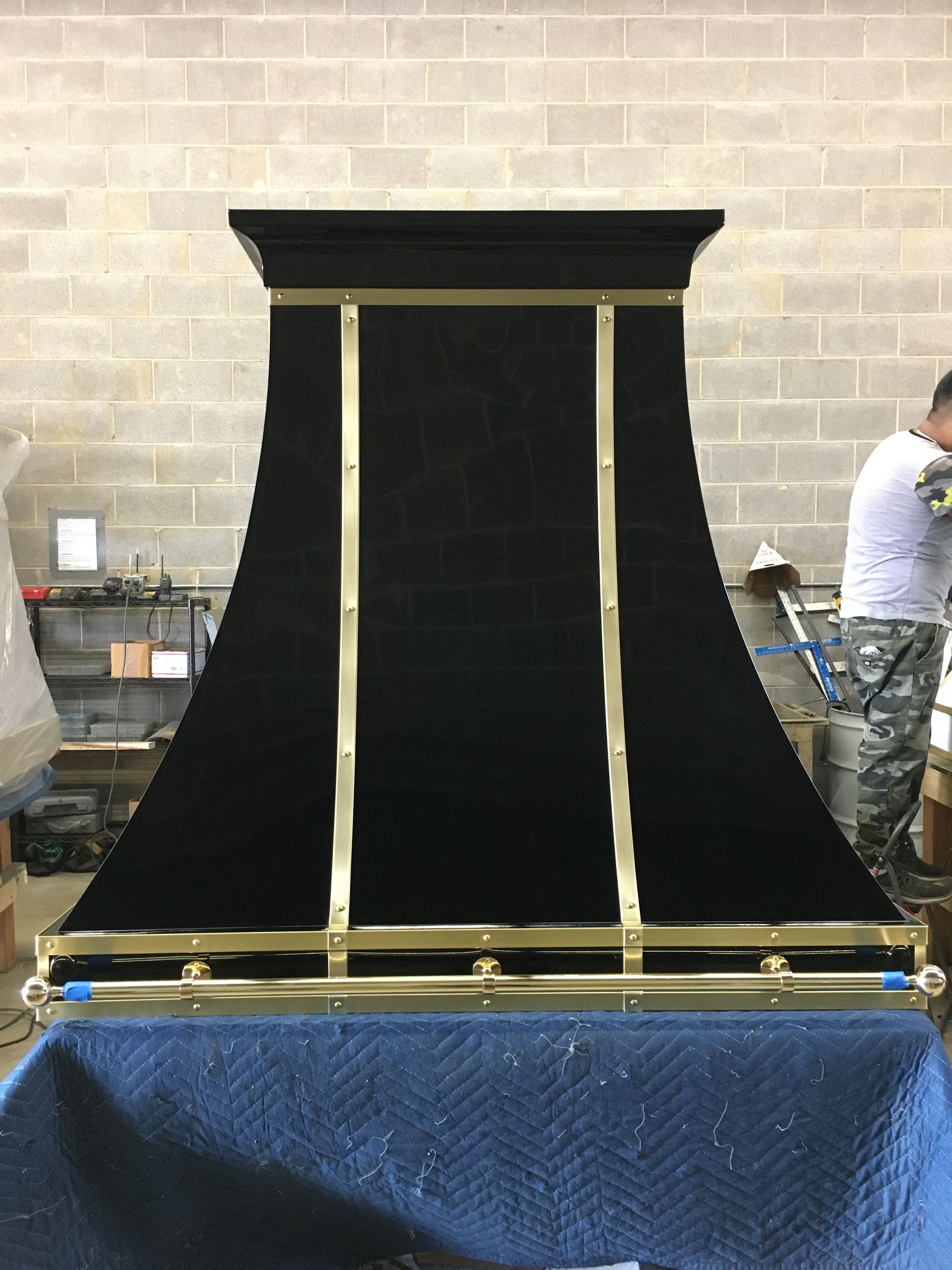 A man is working on a black and gold hood in a room.