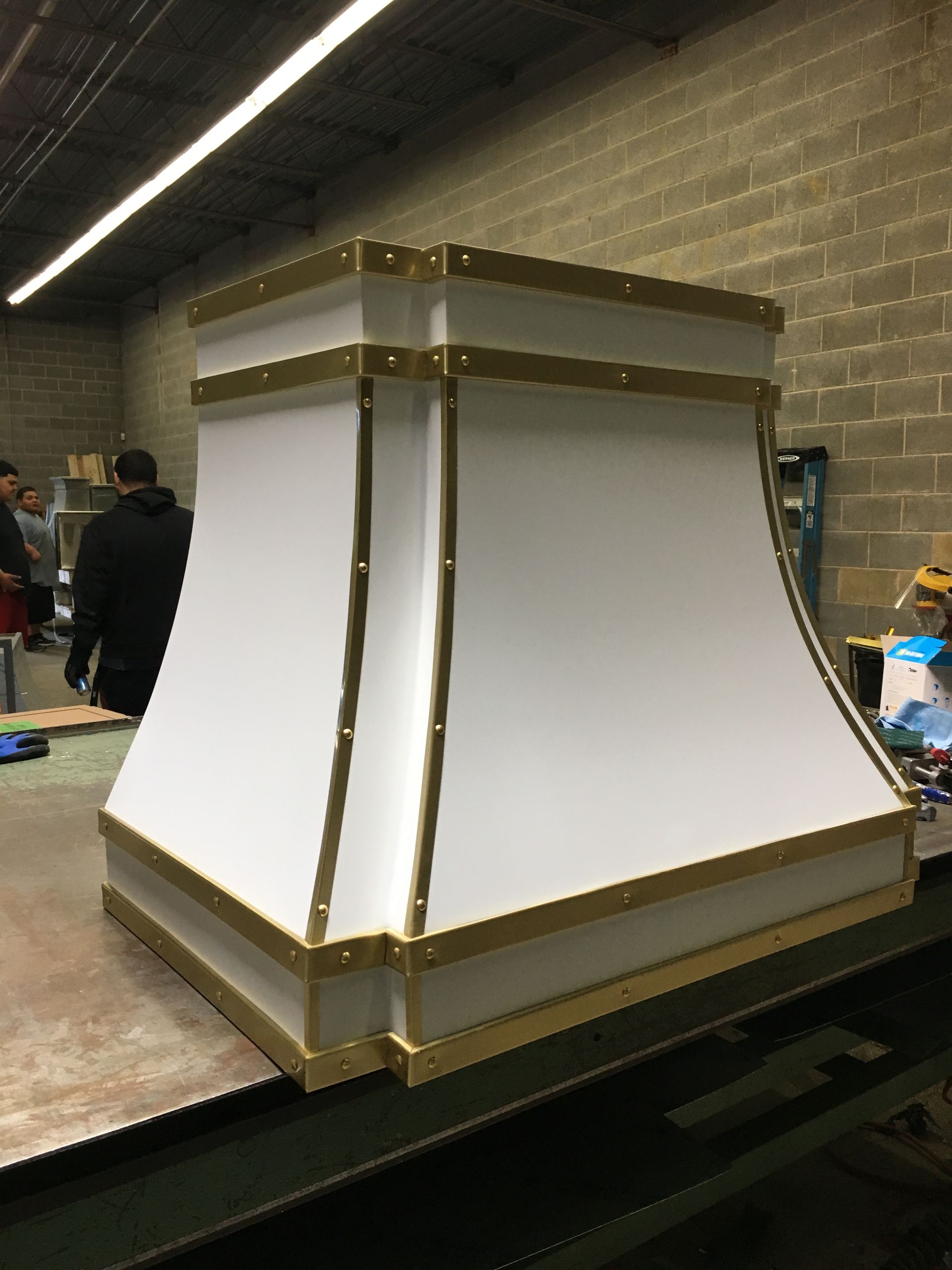 A white lampshade with gold trim is sitting on a table in a room.