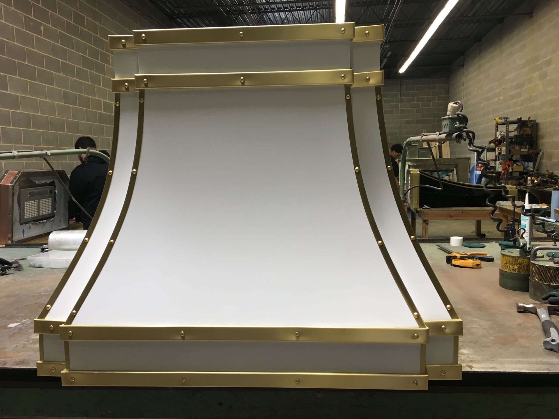 A white hood with brass trim is sitting on a table