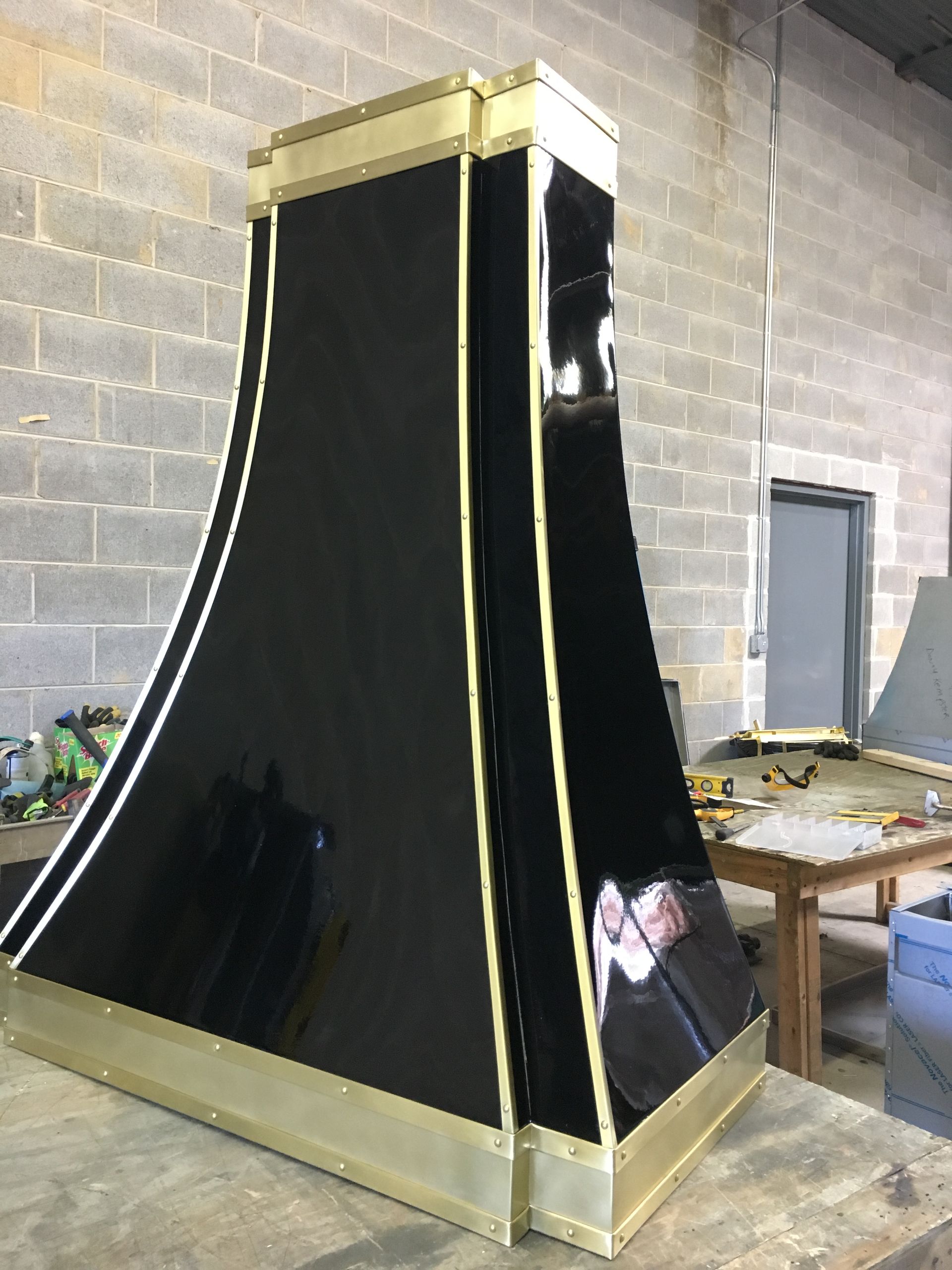 A black and gold hood is sitting on top of a wooden table.