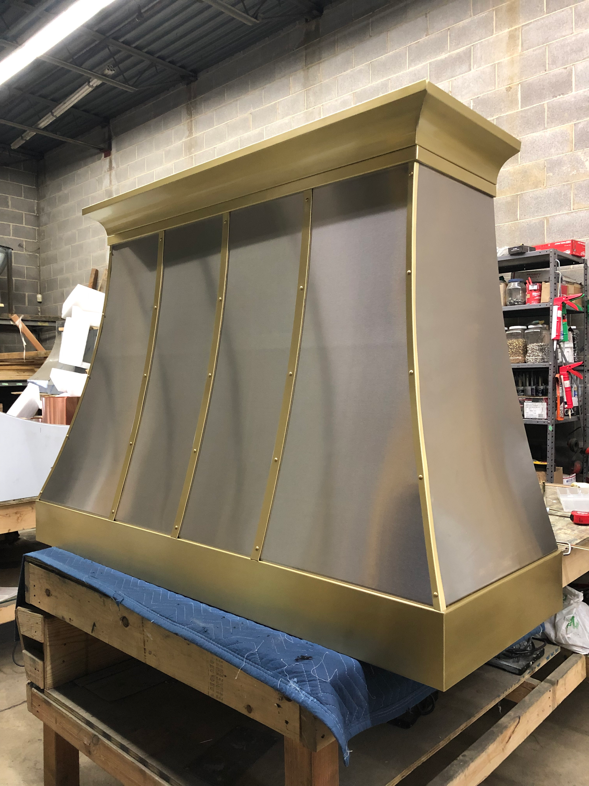 A large stainless steel hood is sitting on top of a wooden table.