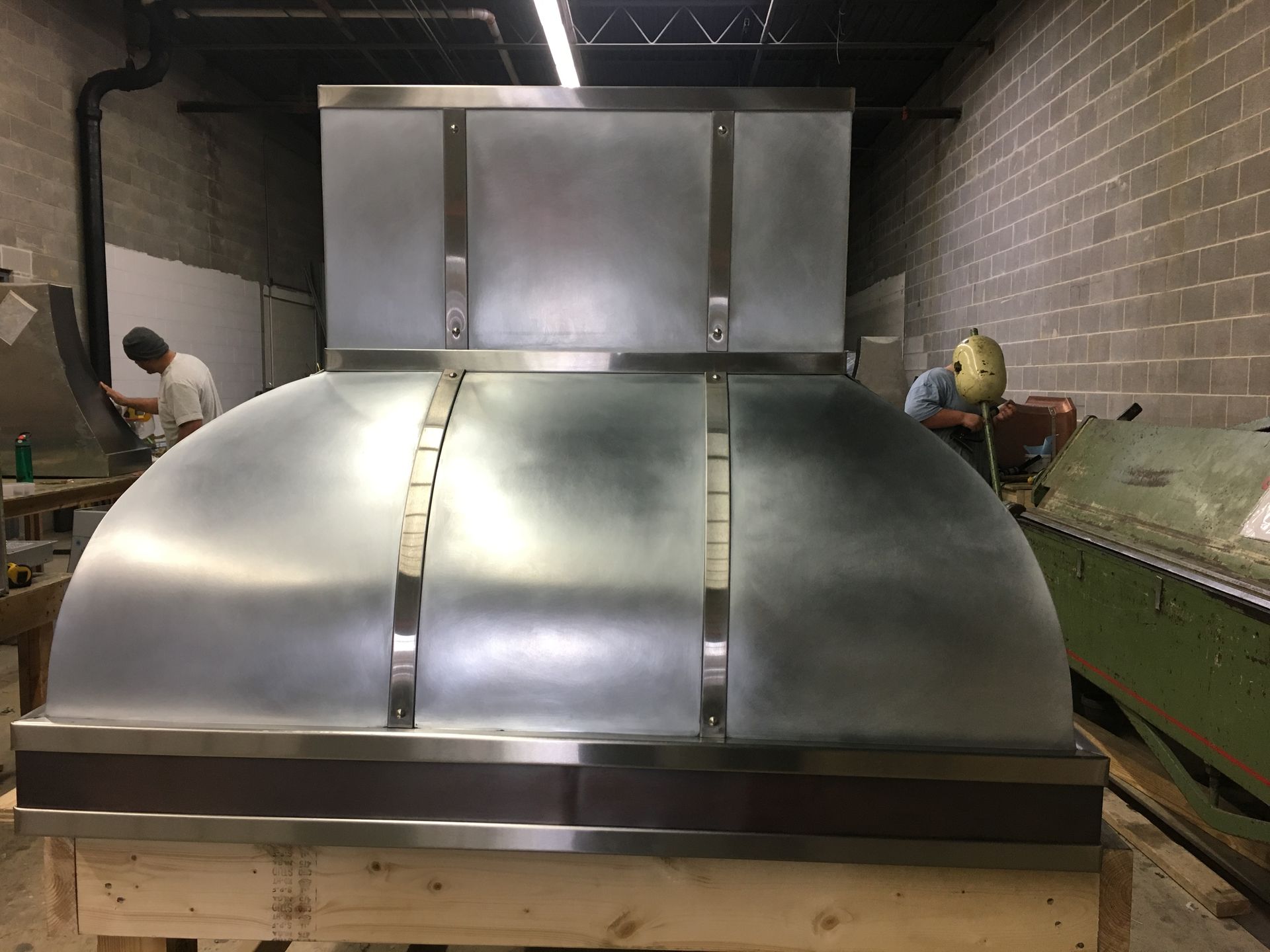 A stainless steel hood is sitting on a wooden crate in a room.