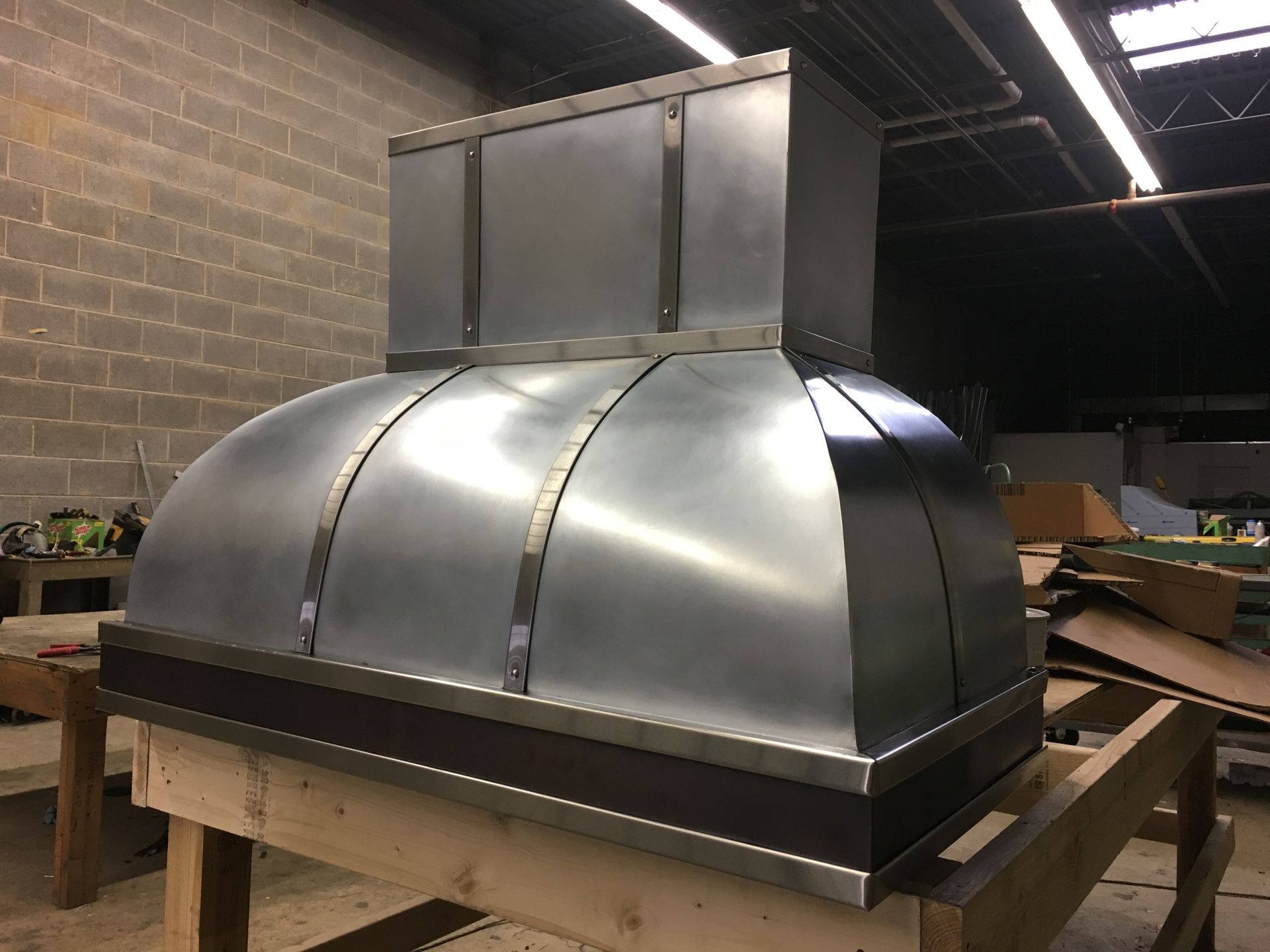 A stainless steel hood is sitting on top of a wooden table.