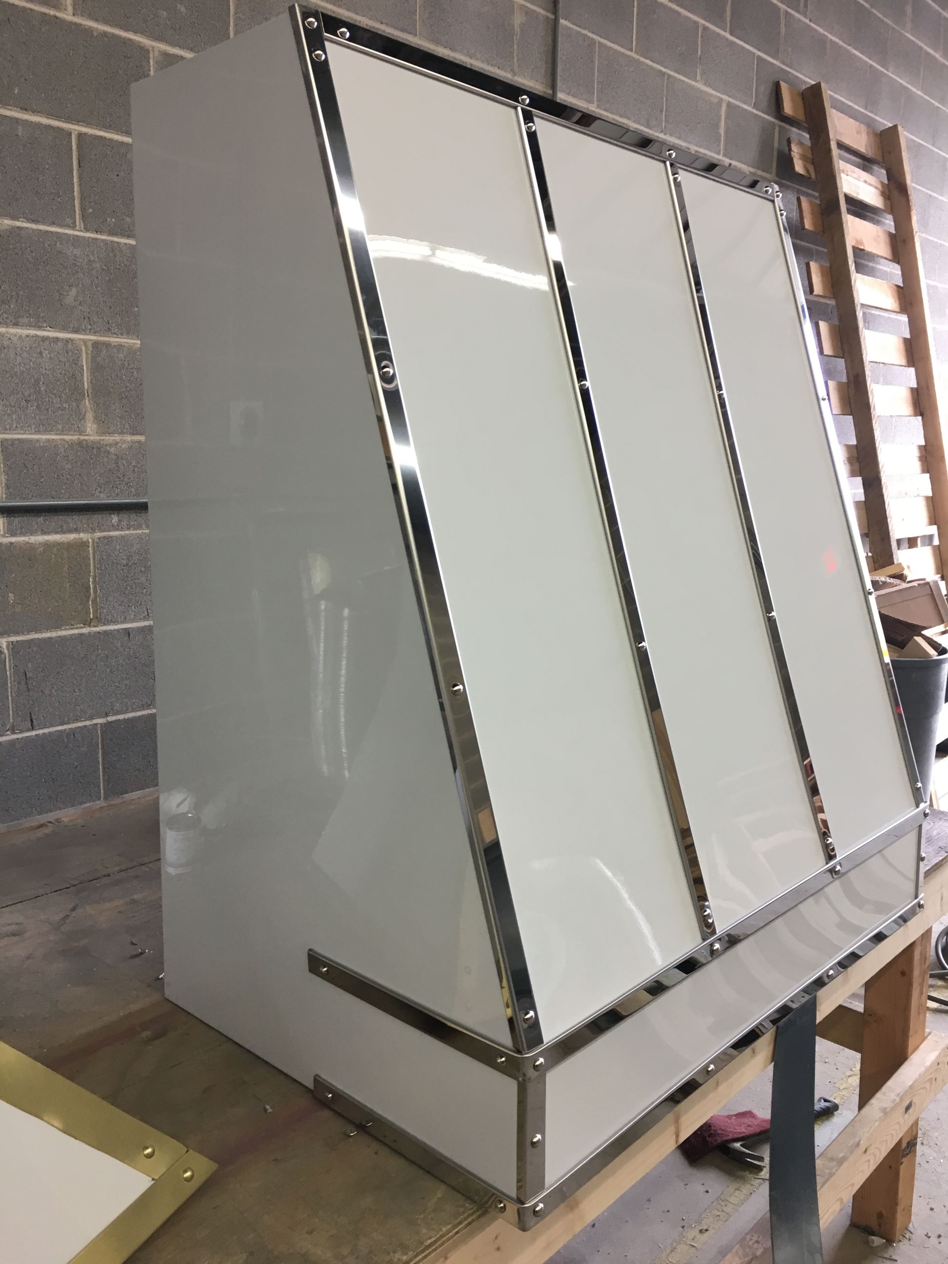 A white box is sitting on a wooden table in front of a brick wall