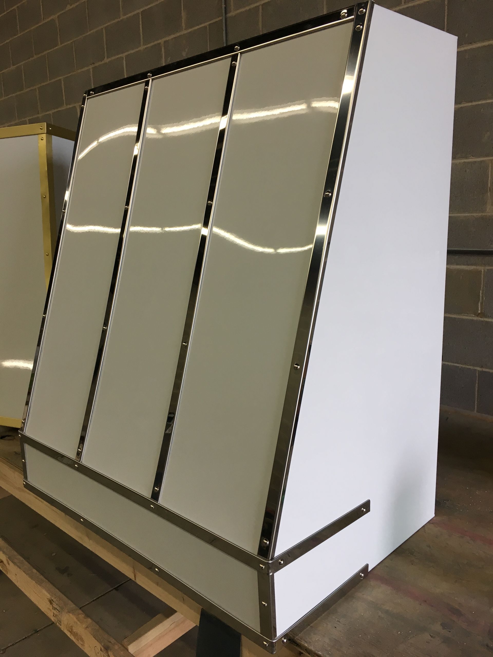 A white cabinet is sitting on a wooden table in front of a brick wall.