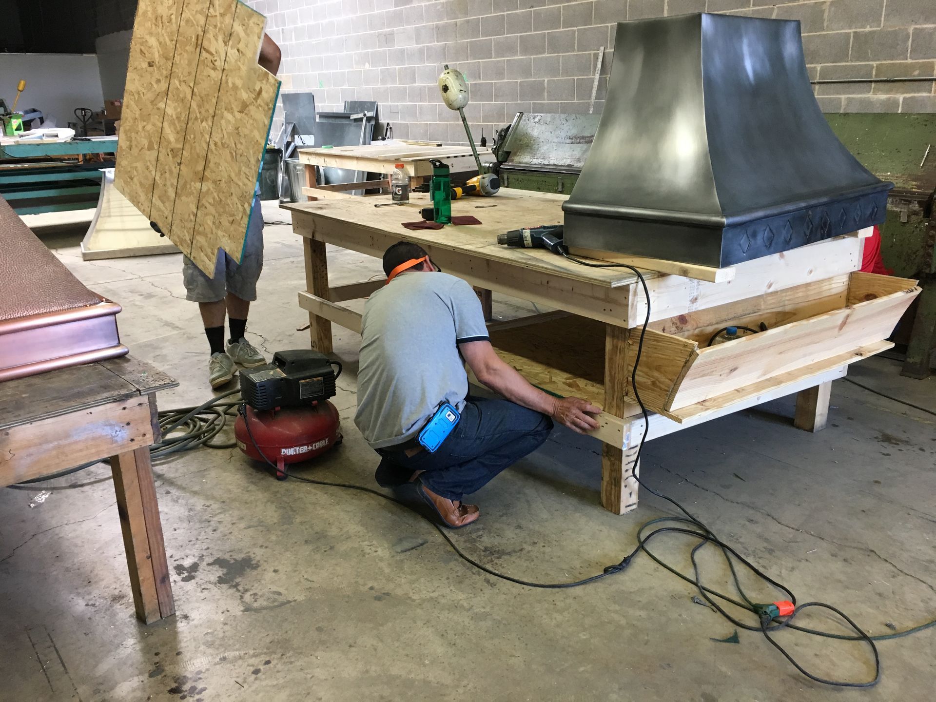 A man is working on a wooden table in a workshop.