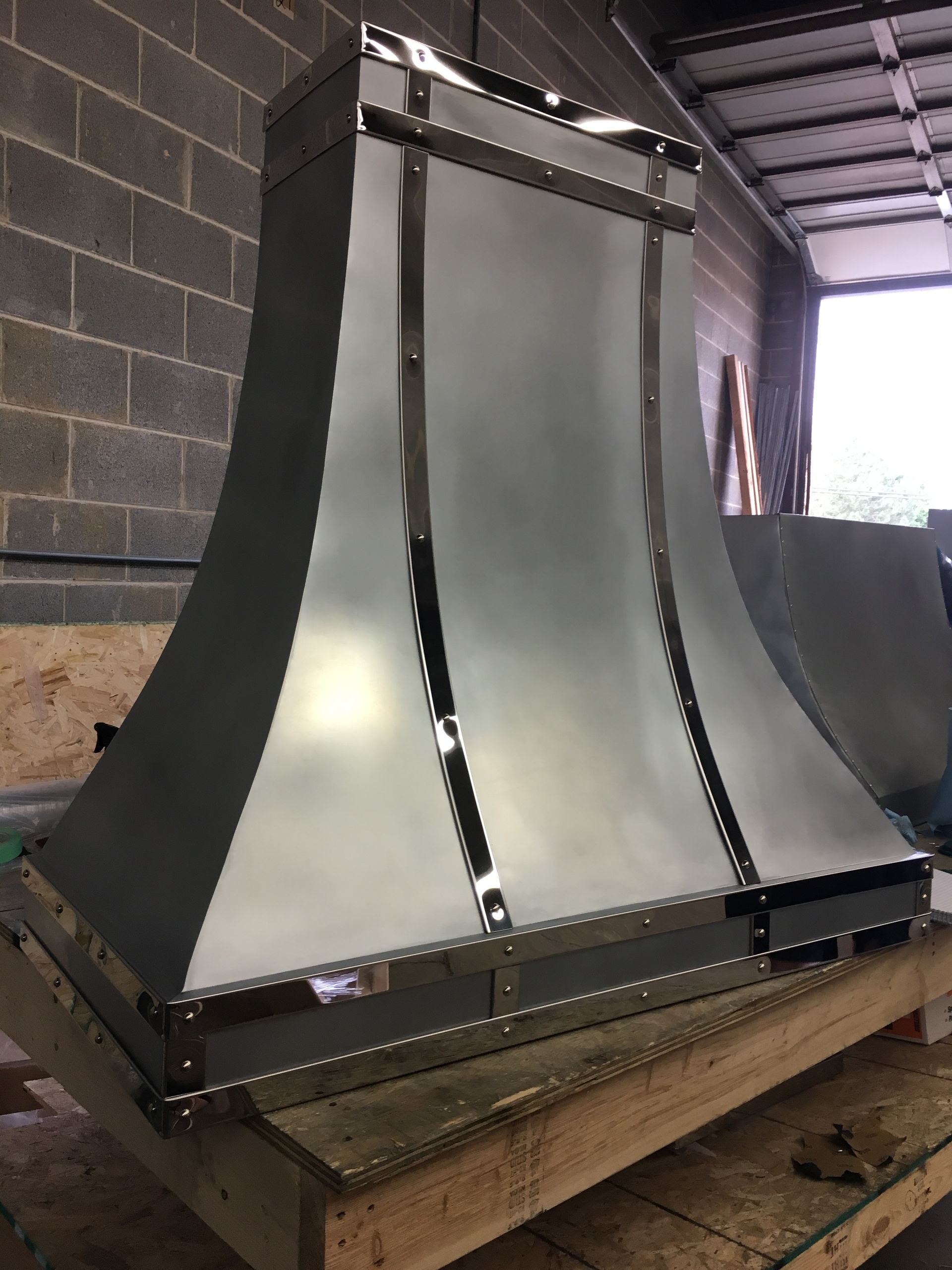 A stainless steel hood is sitting on top of a wooden table.