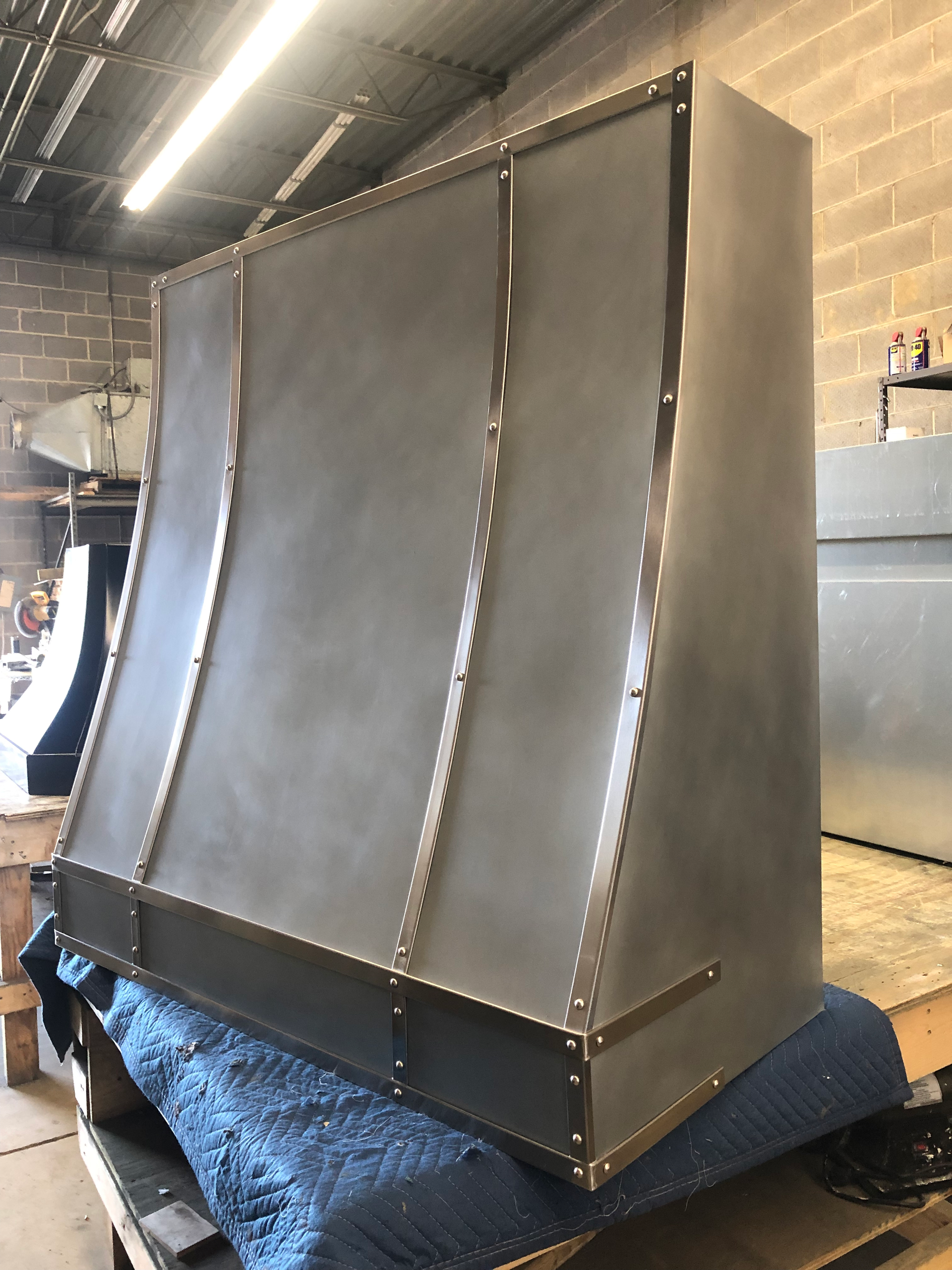 A stainless steel hood is sitting on top of a blue blanket in a room.