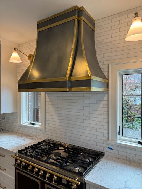 A kitchen with a stove top oven and a hood above it.