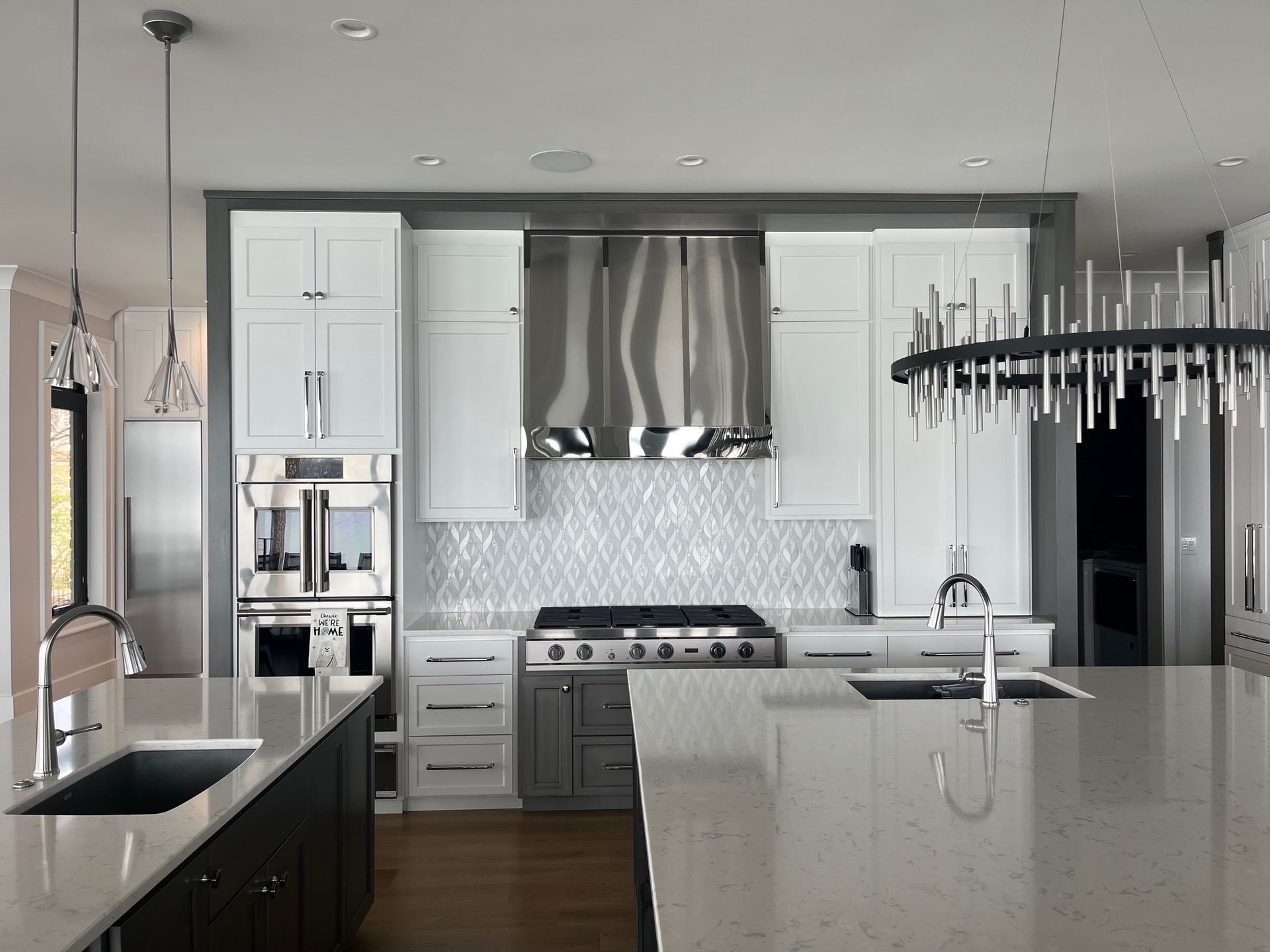 A kitchen with white cabinets , stainless steel appliances and a large island.