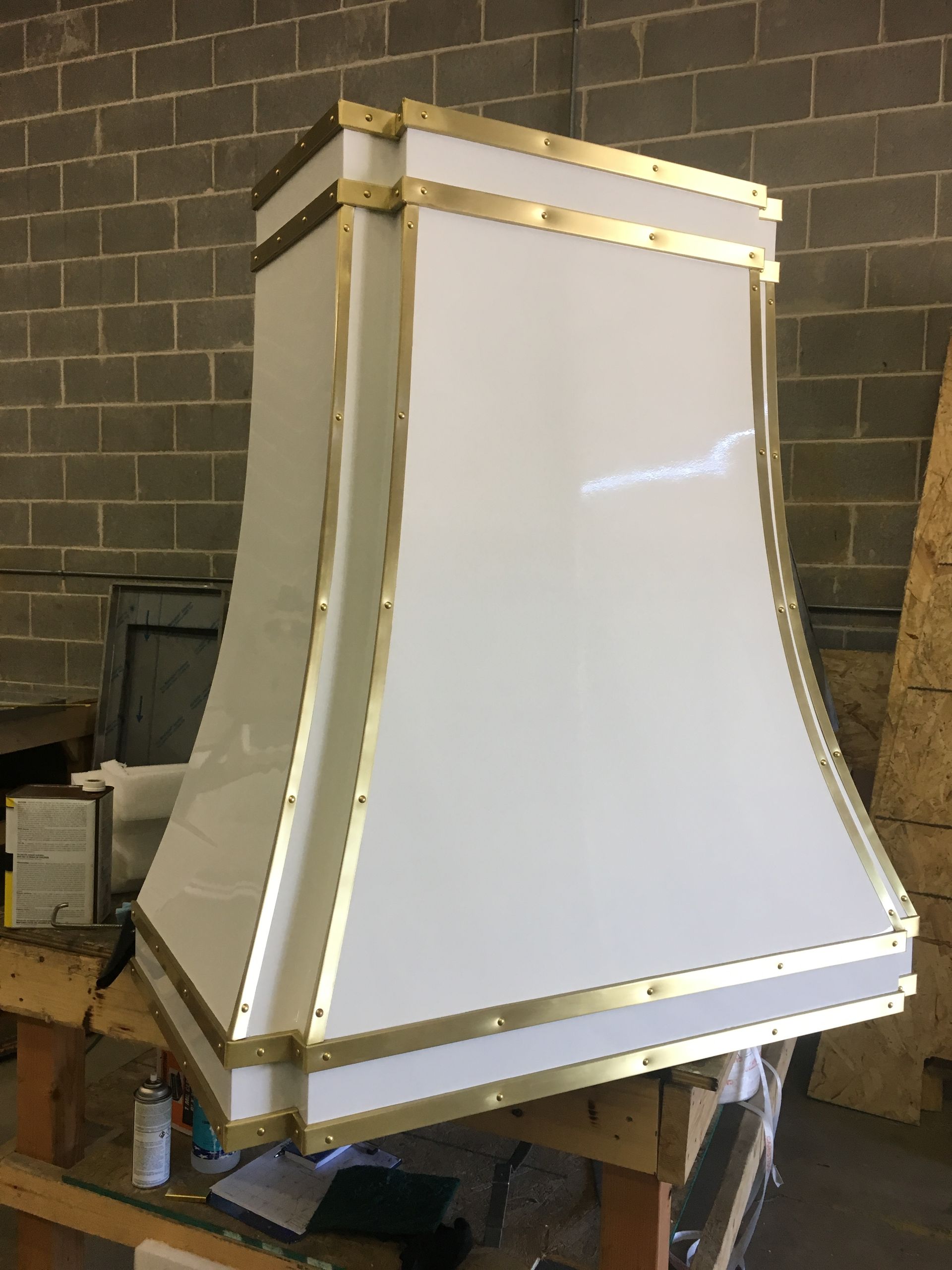 A white lamp sitting on top of a wooden table in front of a brick wall.